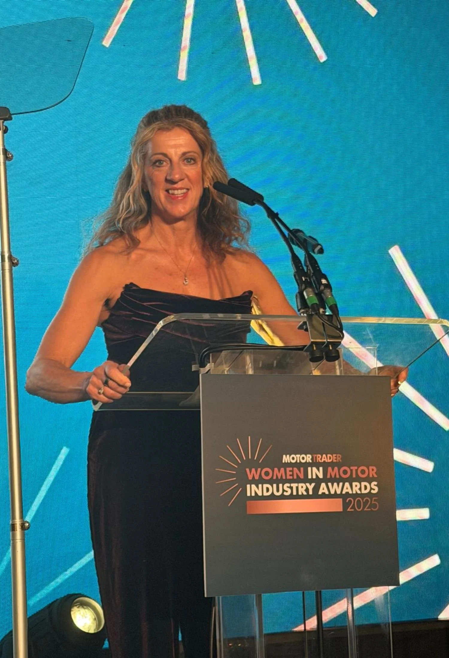 Sally Gunnell  at a podium speaking at the Women in Motor Industry Awards 2025 event.