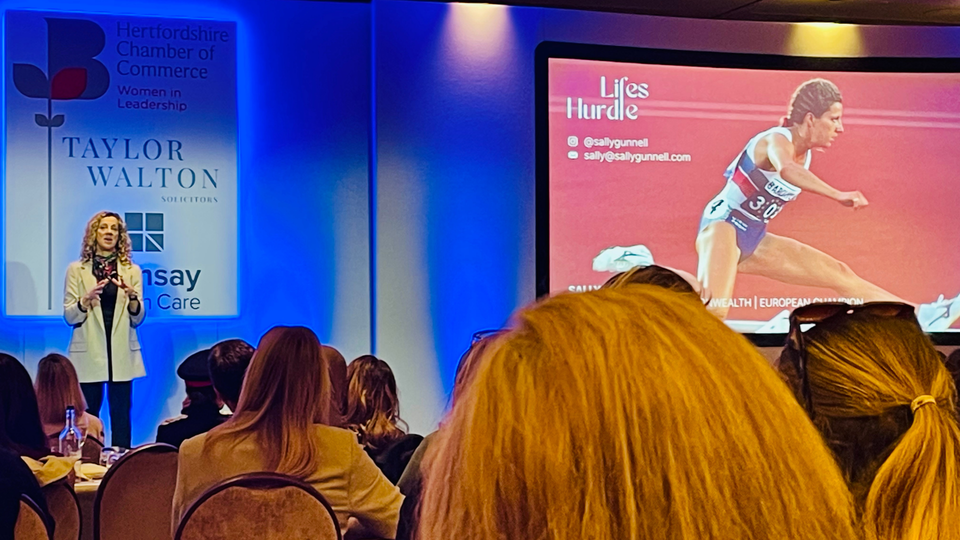Sally Gunnell on stage giving a presentation at a conference.