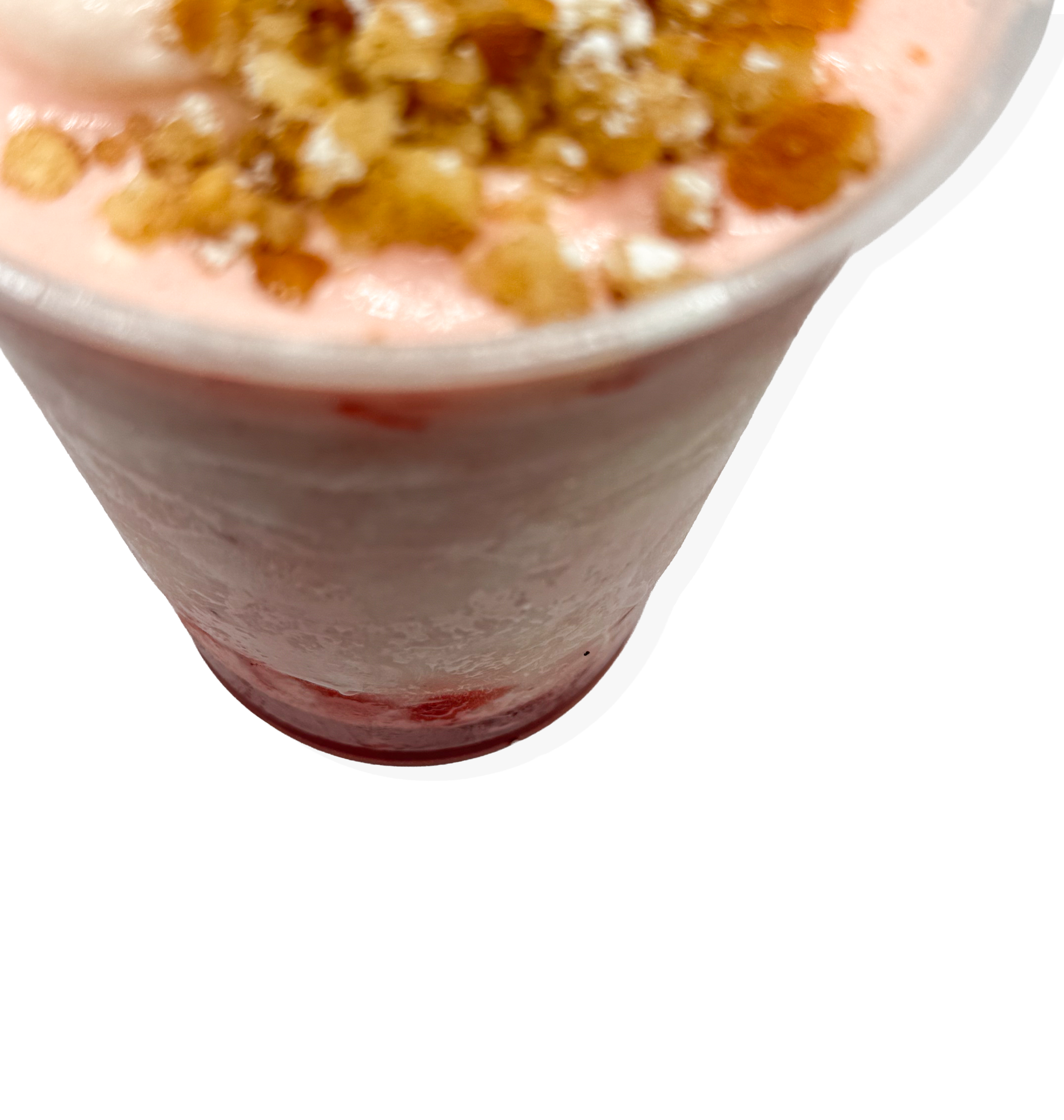 A pink milkshake topped with crushed nuts or cookie crumbs in a clear tall glass.