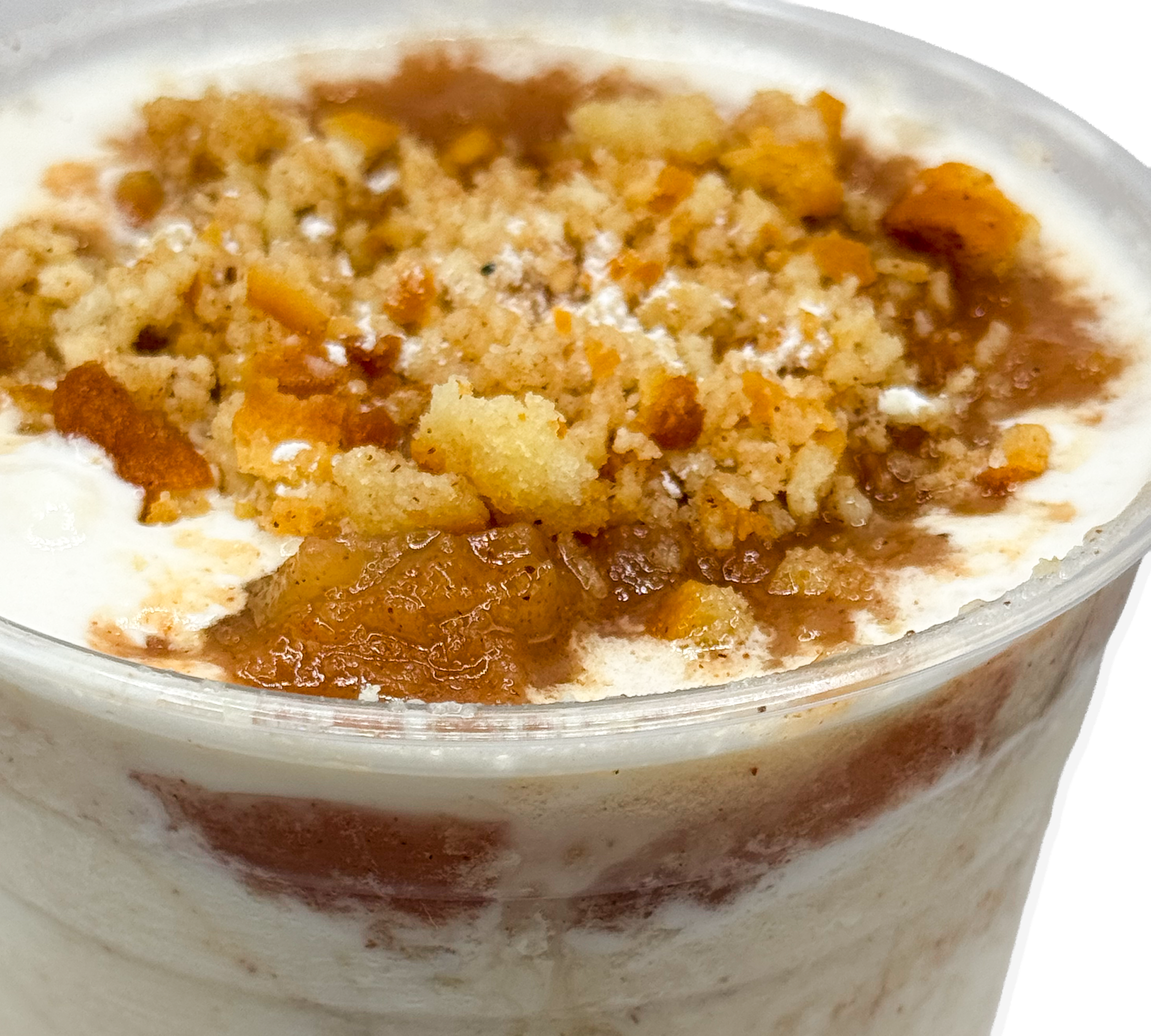 Close-up of a dessert with a crumble topping, caramel sauce, and whipped cream in a clear bowl.