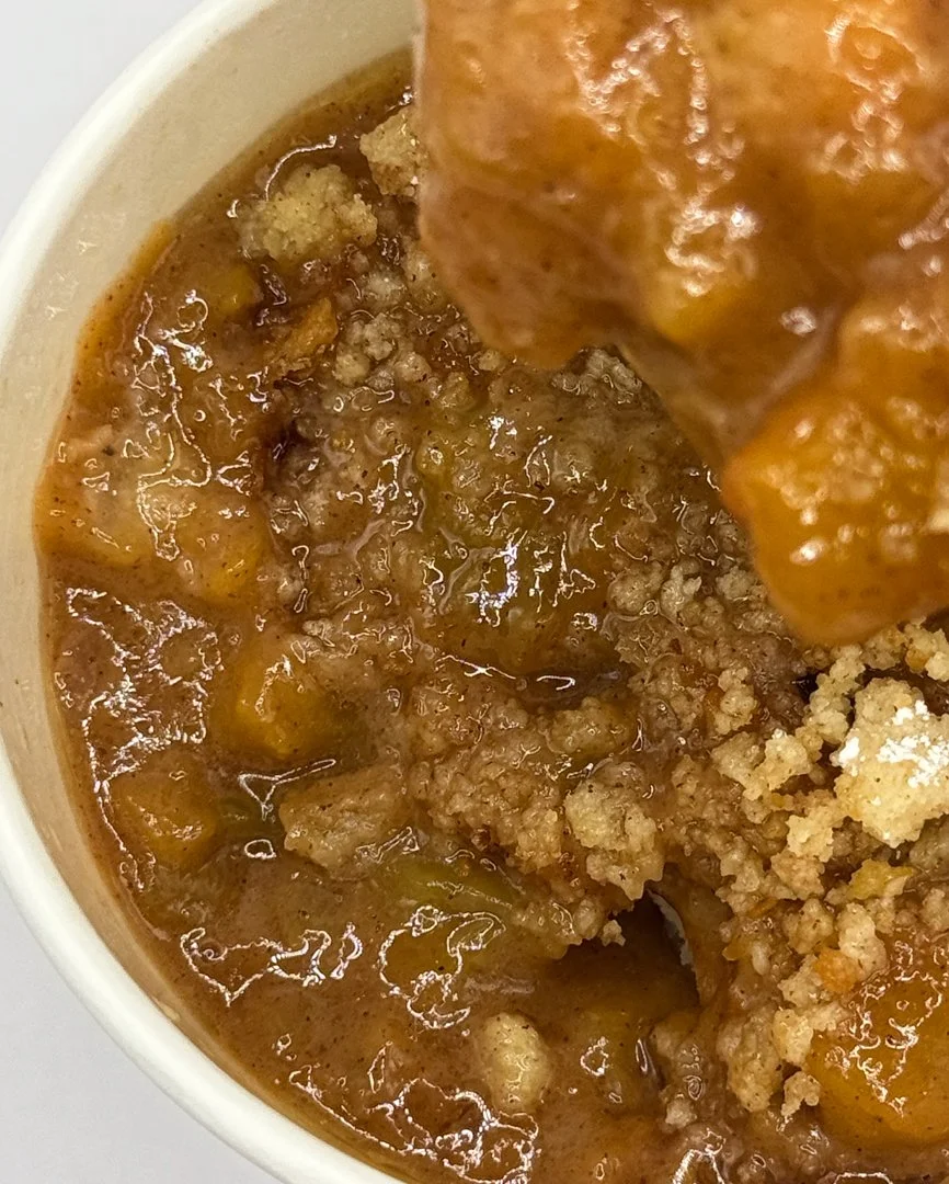 Close-up of a bowl of chili with ground beef, beans, and tomato sauce, topped with a piece of cornbread.