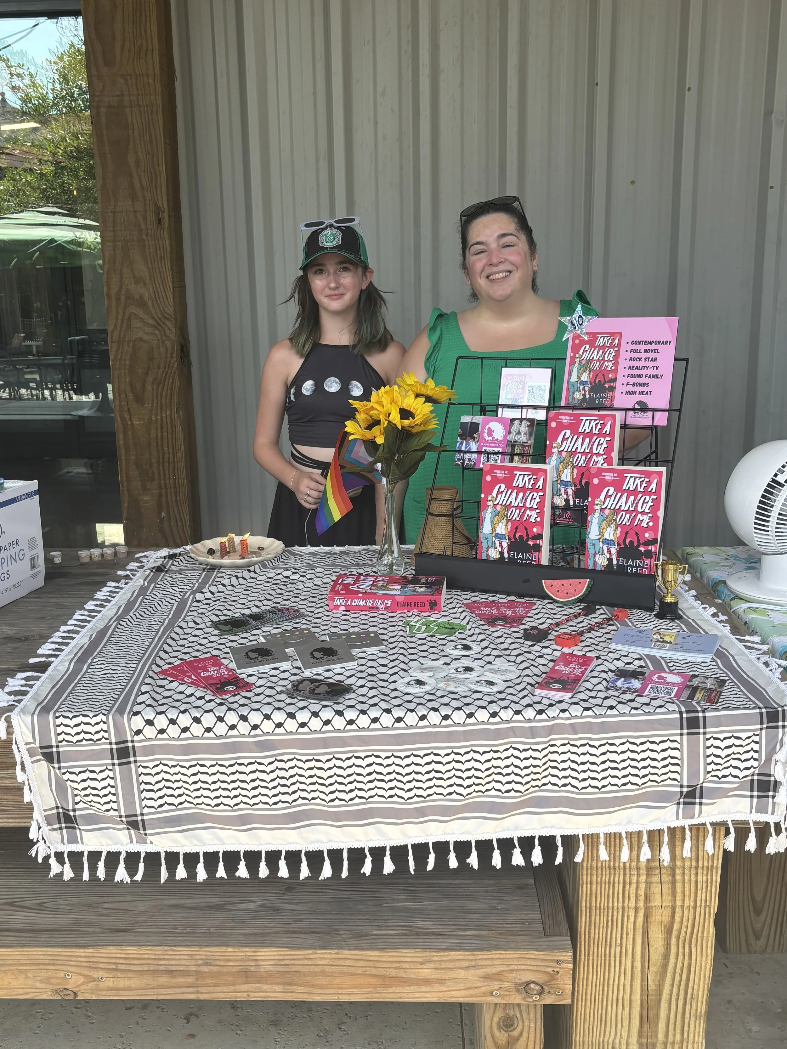 A woman and a girl stand behind a table set up for a book sale.