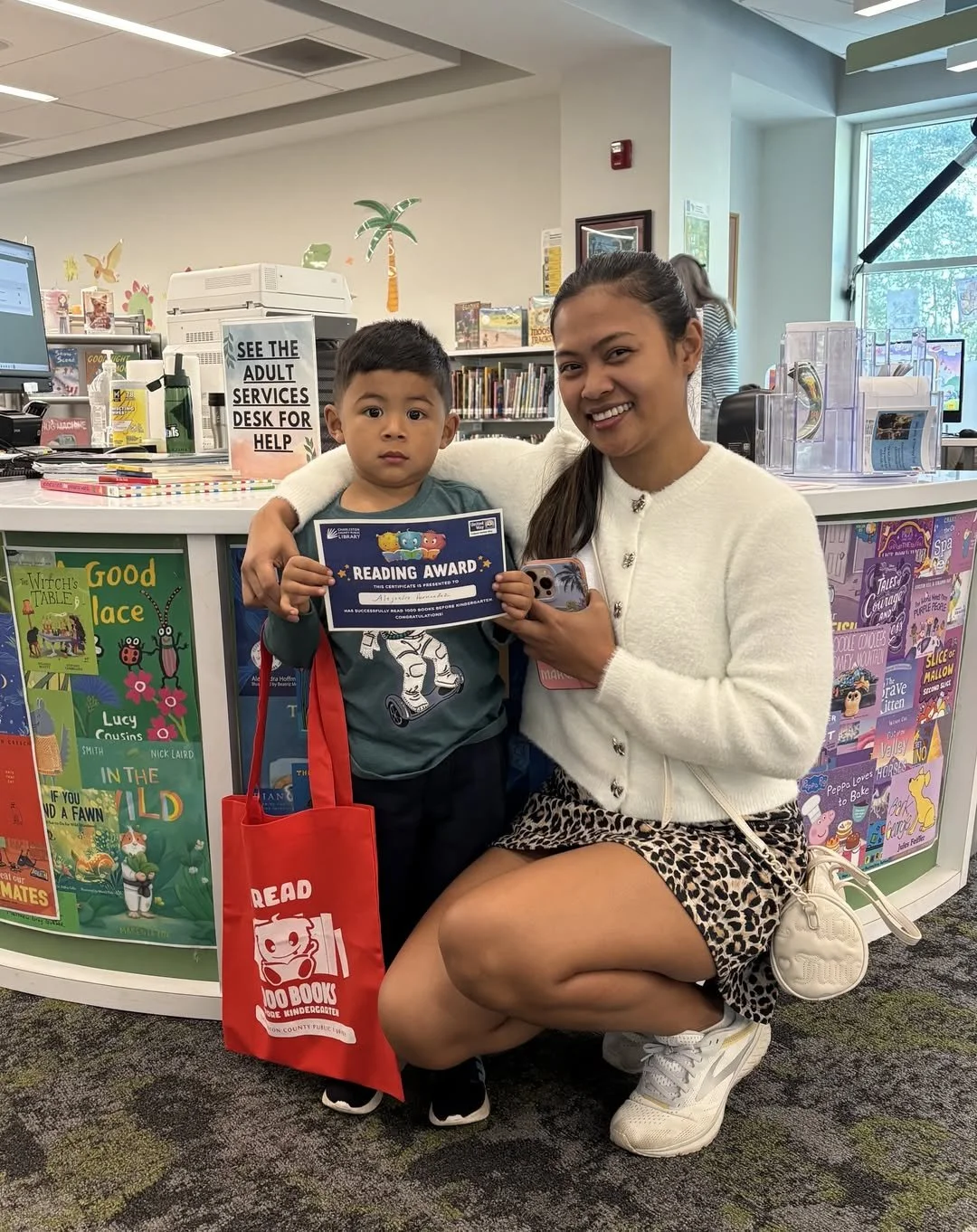 caregiver with child holding a reading award