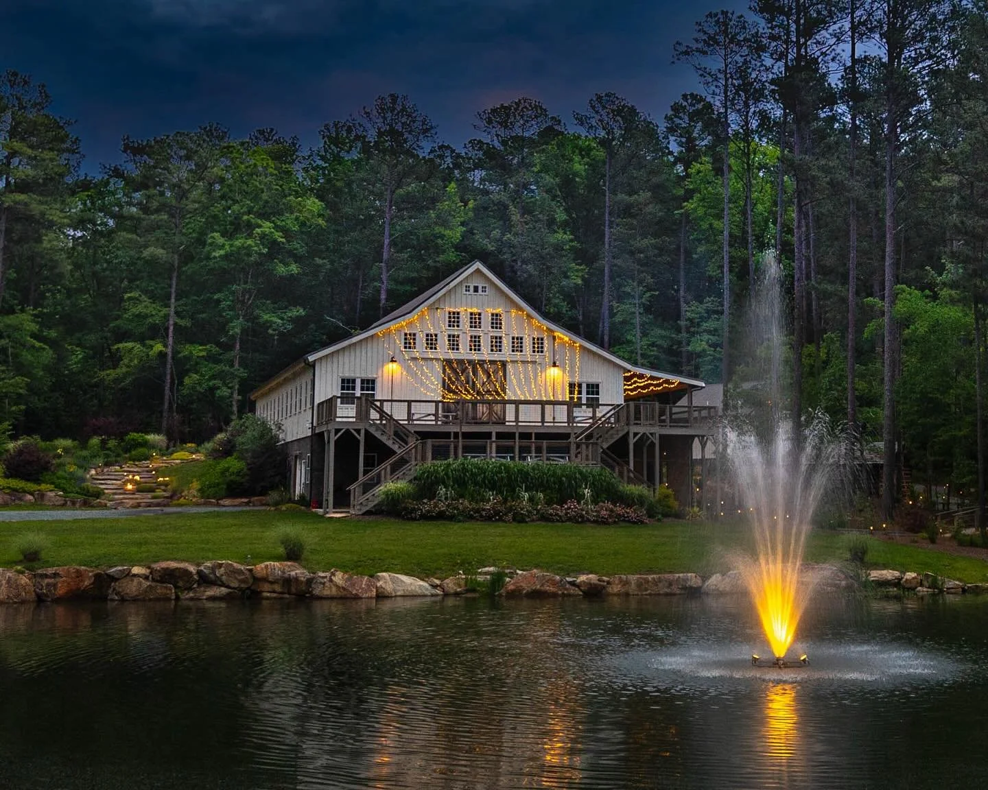 A commercial wedding venue situated on a lake with a freshly manicured lawn and freshly mulched beds.