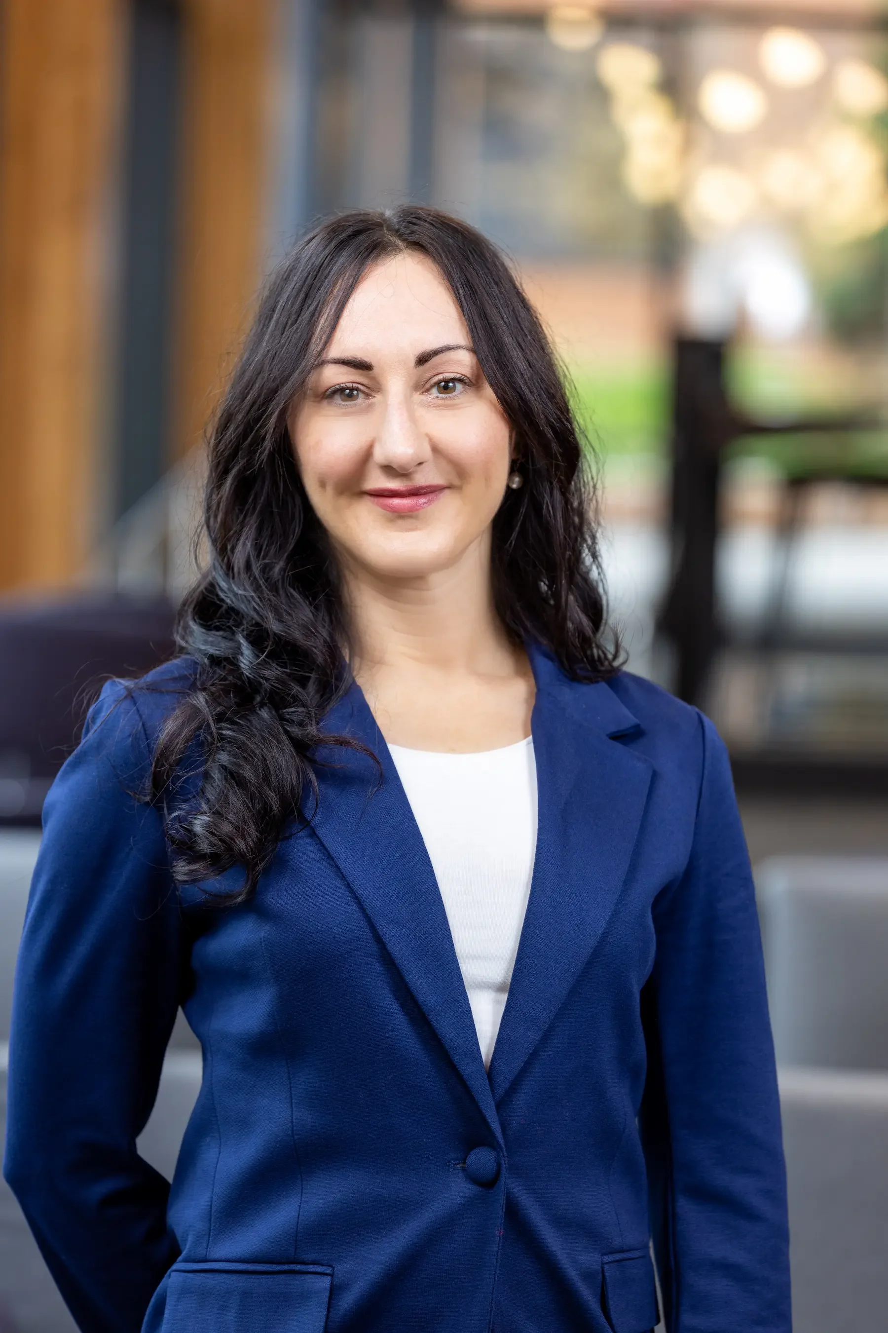 Rachel Gonzalez, an HR operations specialist wearing a blue blazer and white blouse with long dark hair smiling.