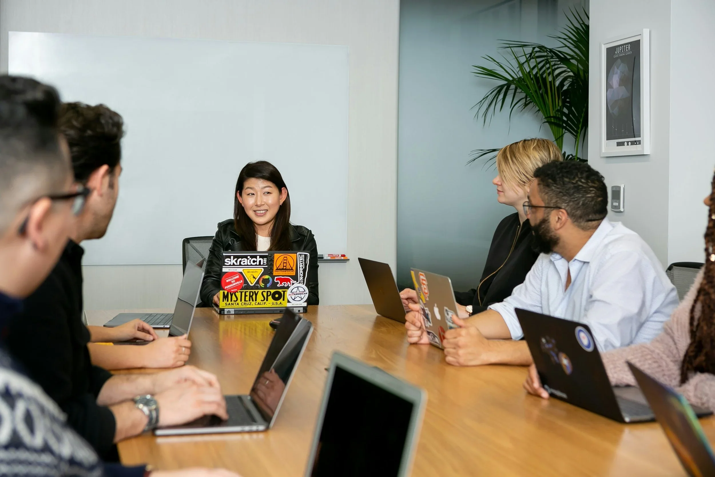 Coworkers in a meeting room with laptops open and smiling.