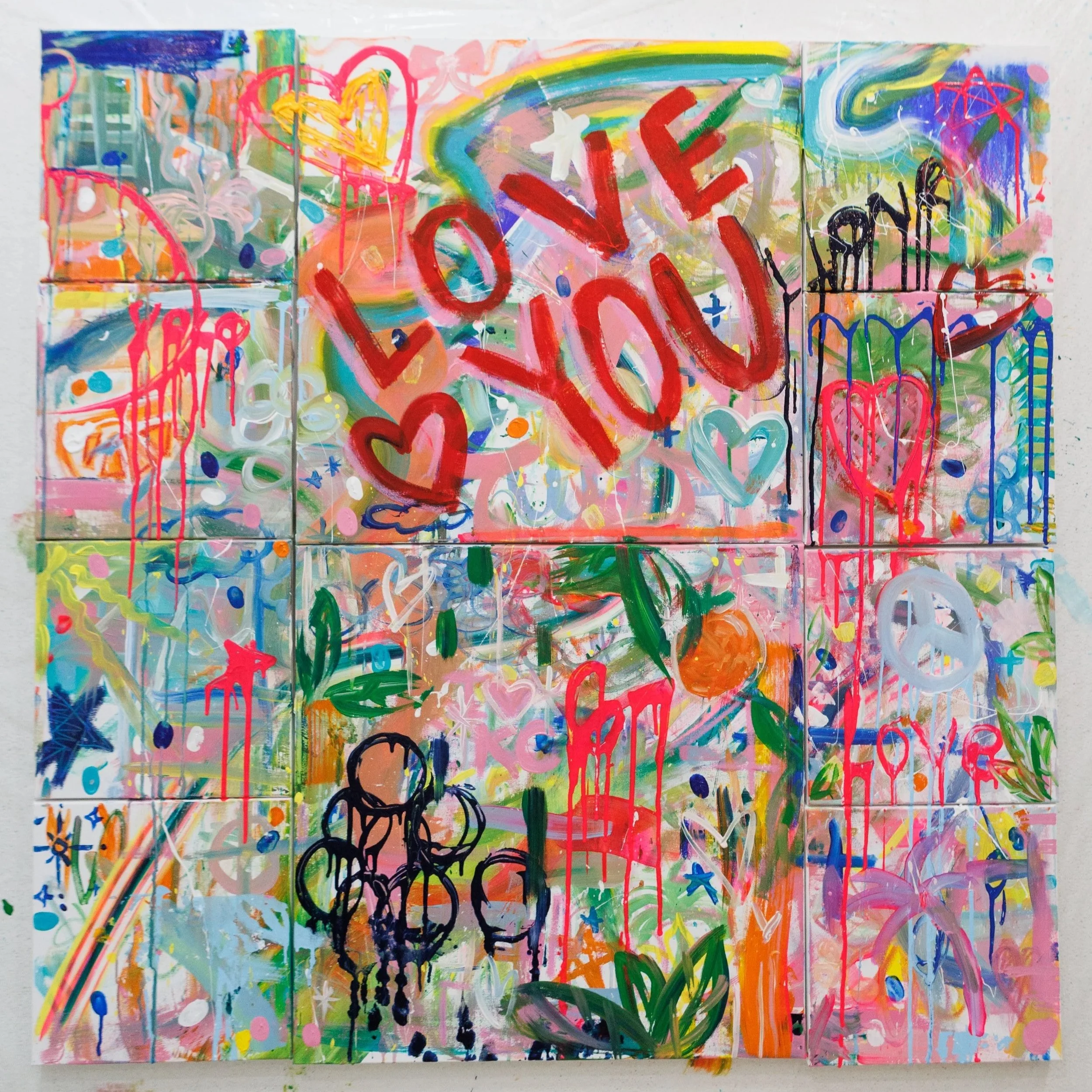 Colorful abstract graffiti art with the words 'LOVE YOU' in red and various hearts, peace signs, flowers, and stars painted over a background of splashes, drips, and bright colors, including pink, blue, green, orange, and yellow.