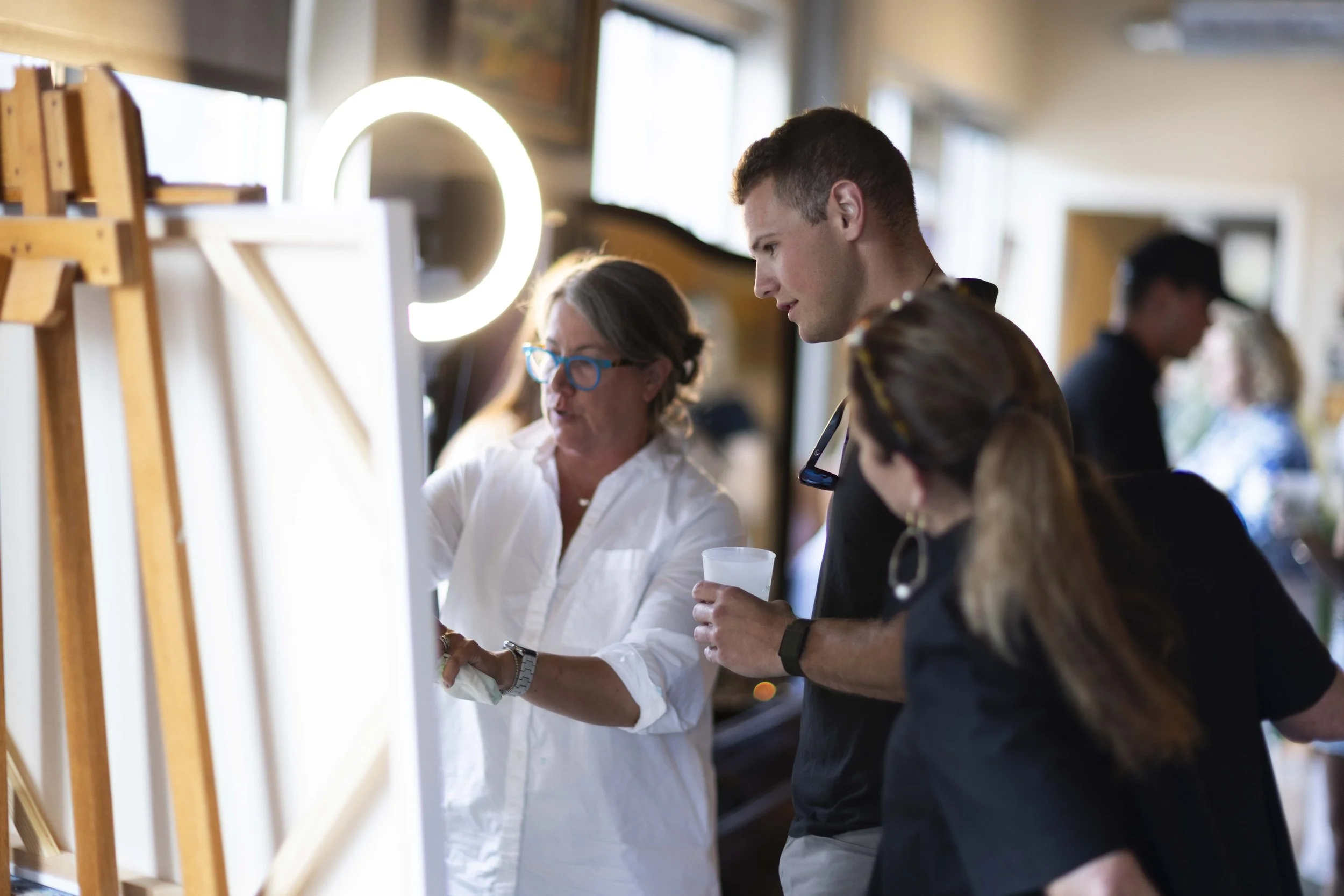 People observing artwork or photographs on display at an indoor gallery or event.