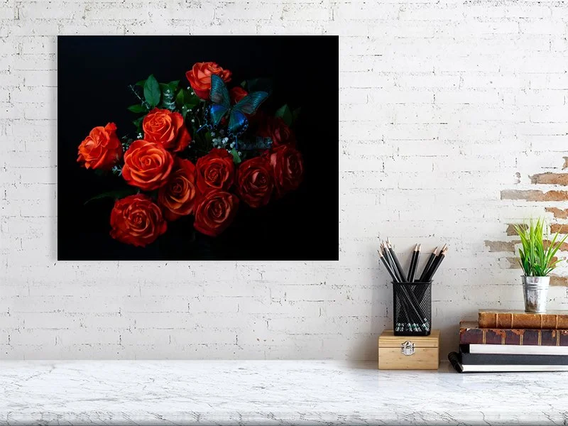 Fine art photograph of an iridescent blue butterfly perched on a bouquet of orange roses for sale sample of home decor.