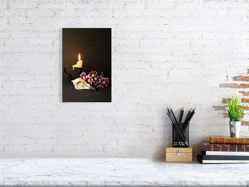 Fine art image of a Raven Skull with Yellow Candle and Purple Daisies on a dark background. For sale, art prints, photograph, home decor, gifts.
