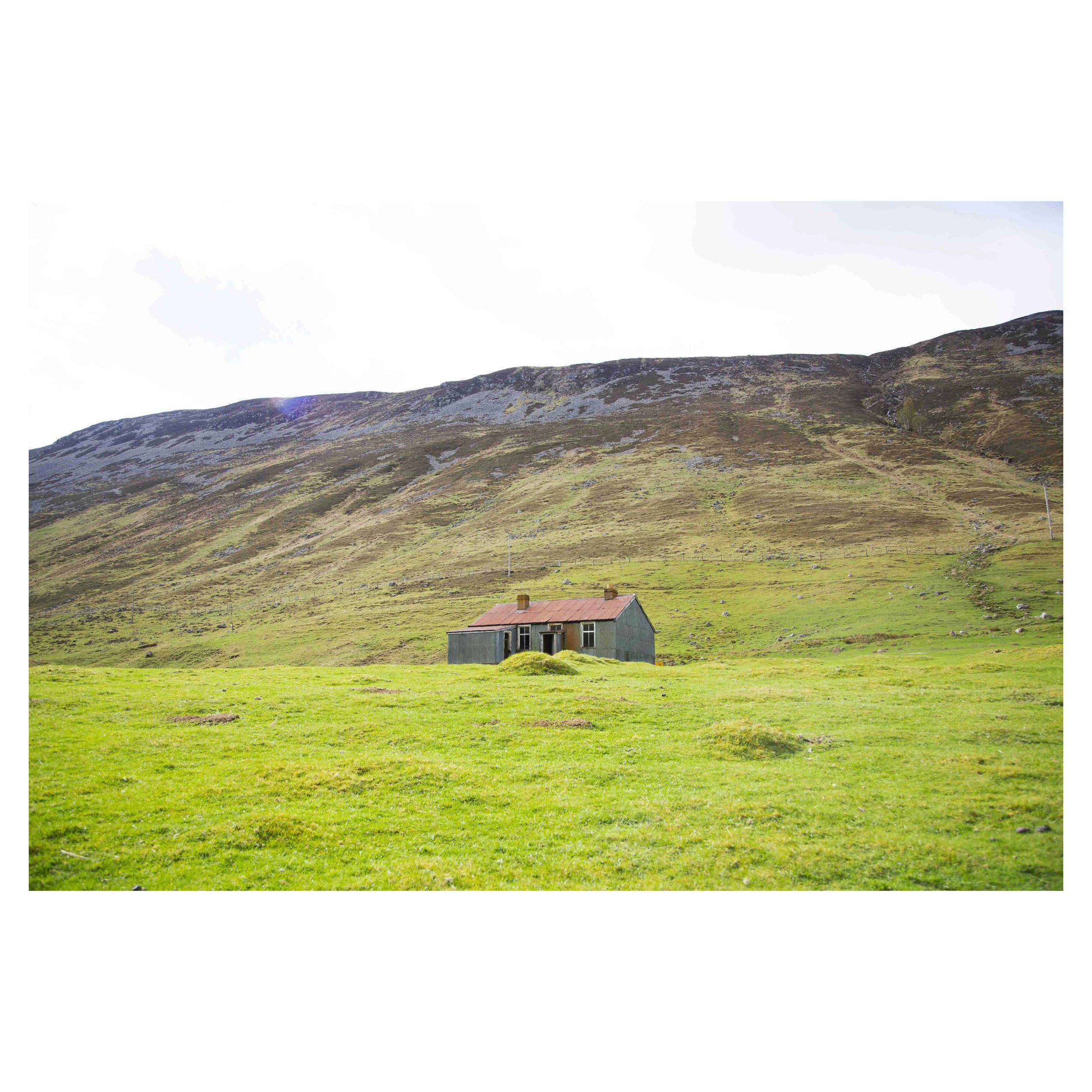 Photograph of an abandoned house in the green hills of a glen in Scotland.