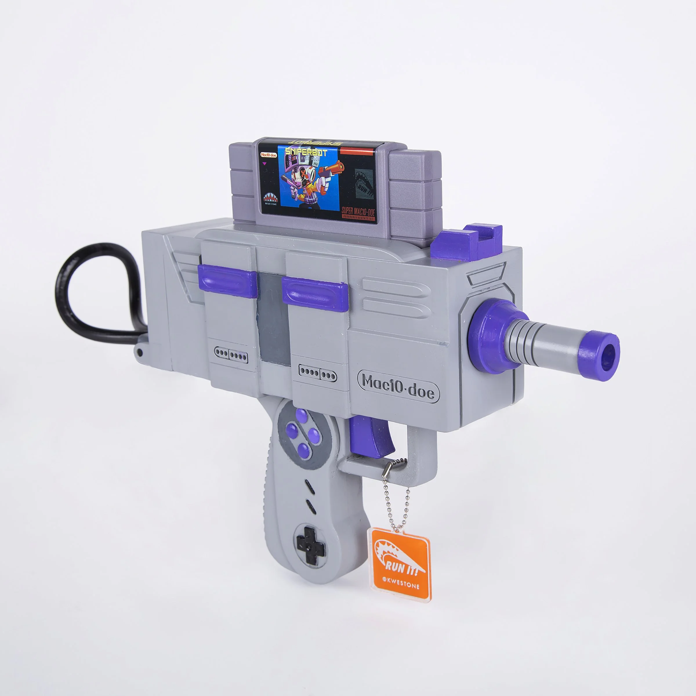 E-commerce image of a one of a kind game cartridge art piece. The piece is designed to look like a Nintendo video game style toy gun. It has an orange tag hanging from it. The gun is grey and purple on a white background.