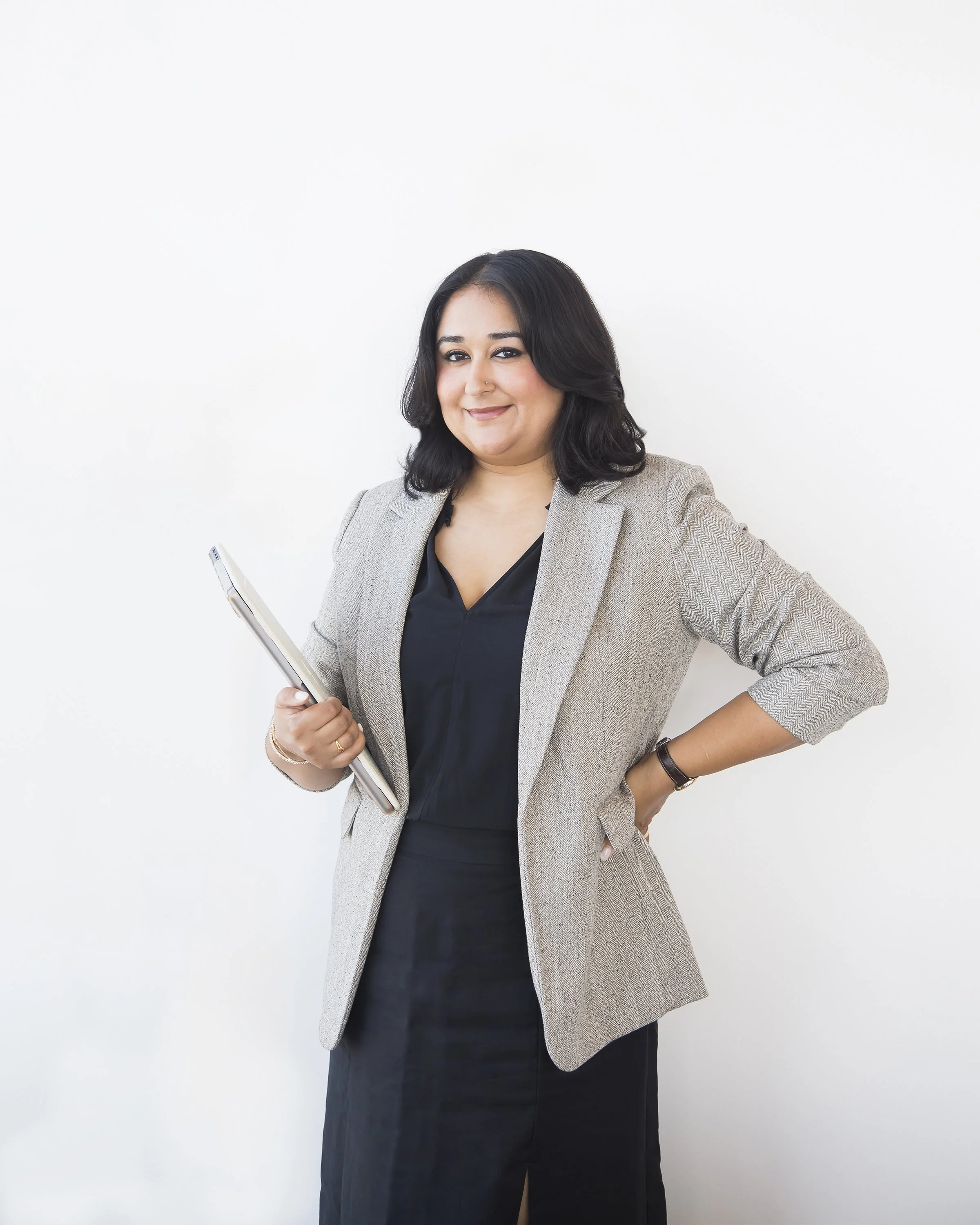 Corporate portrait of an East Asian Indian woman holding a laptop.