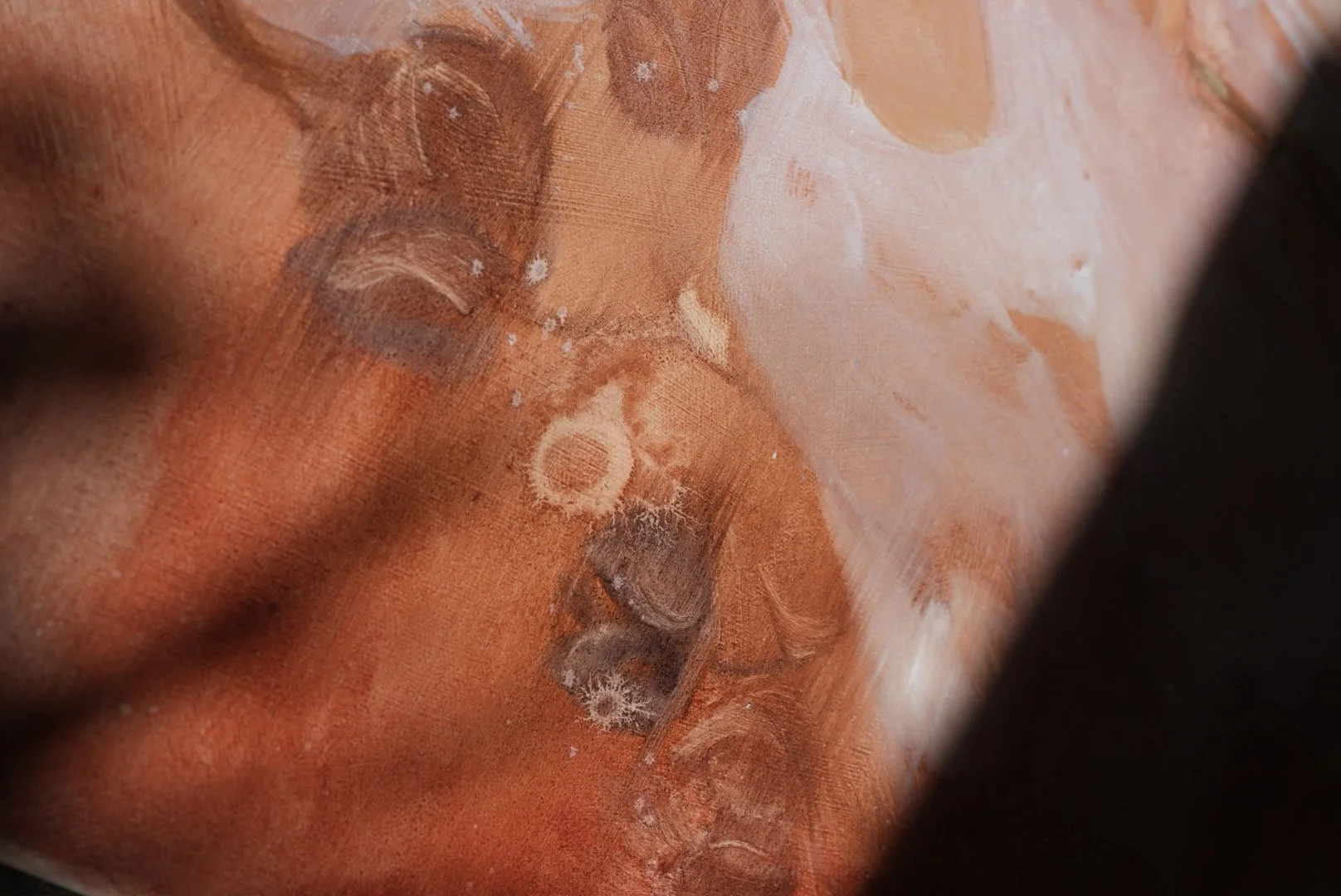 Nahaufnahme einer Statue mit geschlossen Augen, detailsreich in warmen Orangetönen und weißen Akzenten.