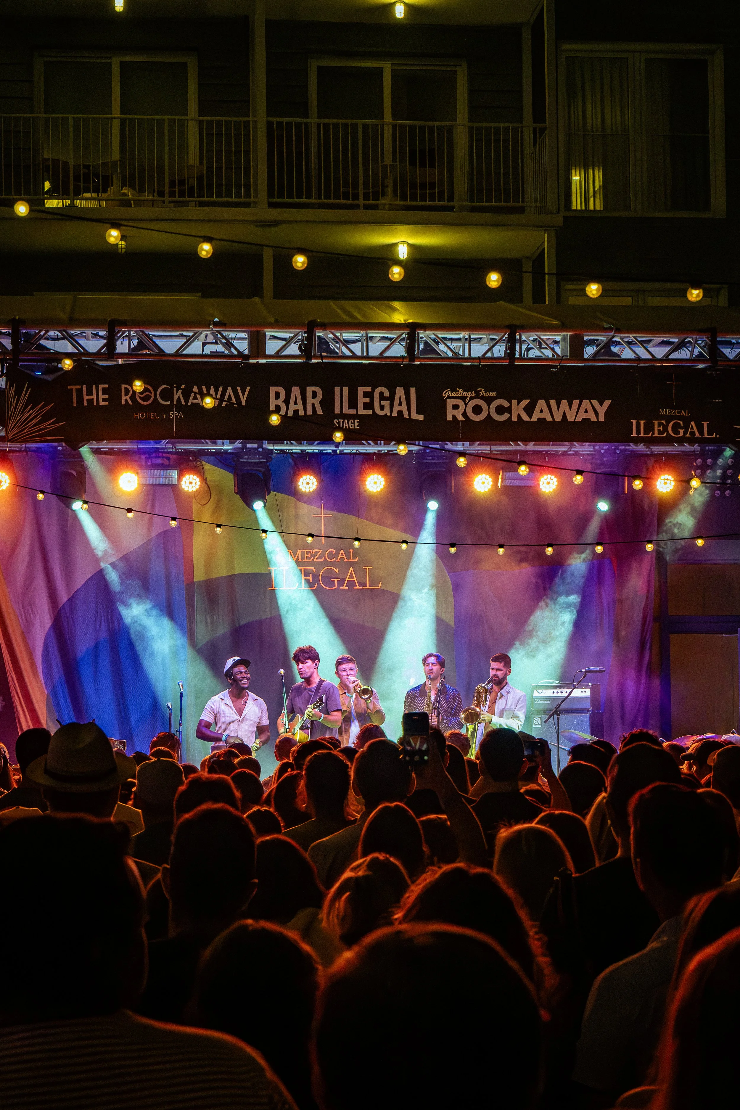 Live band performing on stage at the Rockaway Hotel & Spa with colorful lights and an audience watching.