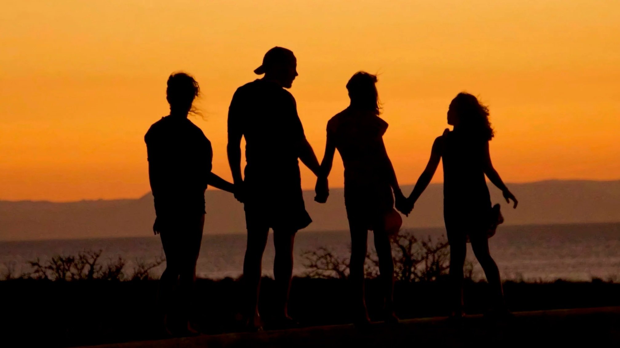 Silueta de familia unida en el atardecer reflexionando sobre la educación de los hijos y valores familiares.