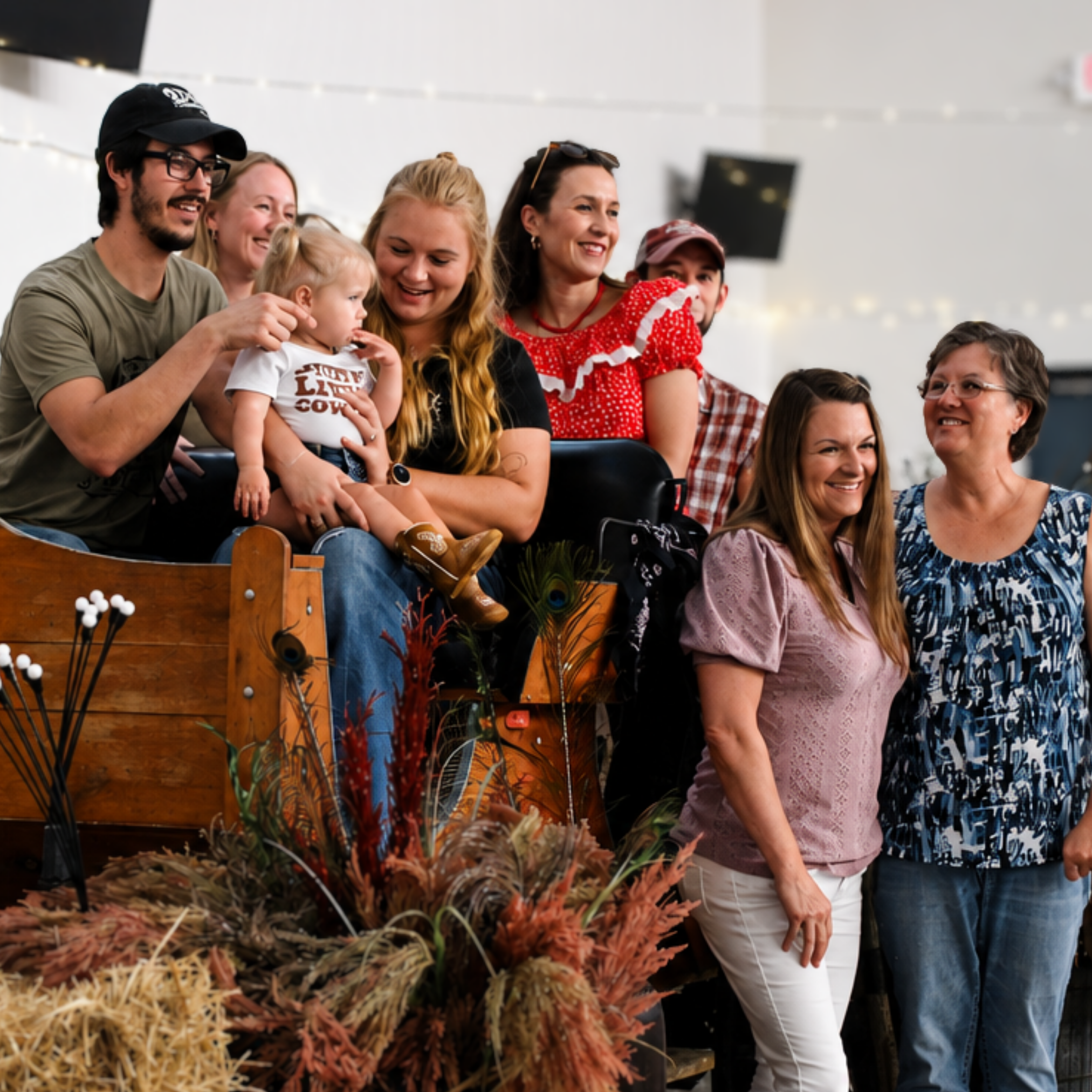 Group of people smiling and looking at a display of fall-themed decorations at an indoor event.