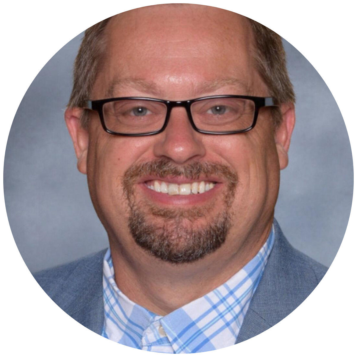 Professional headshot of a smiling man with glasses, a beard, and a checkered dress shirt.