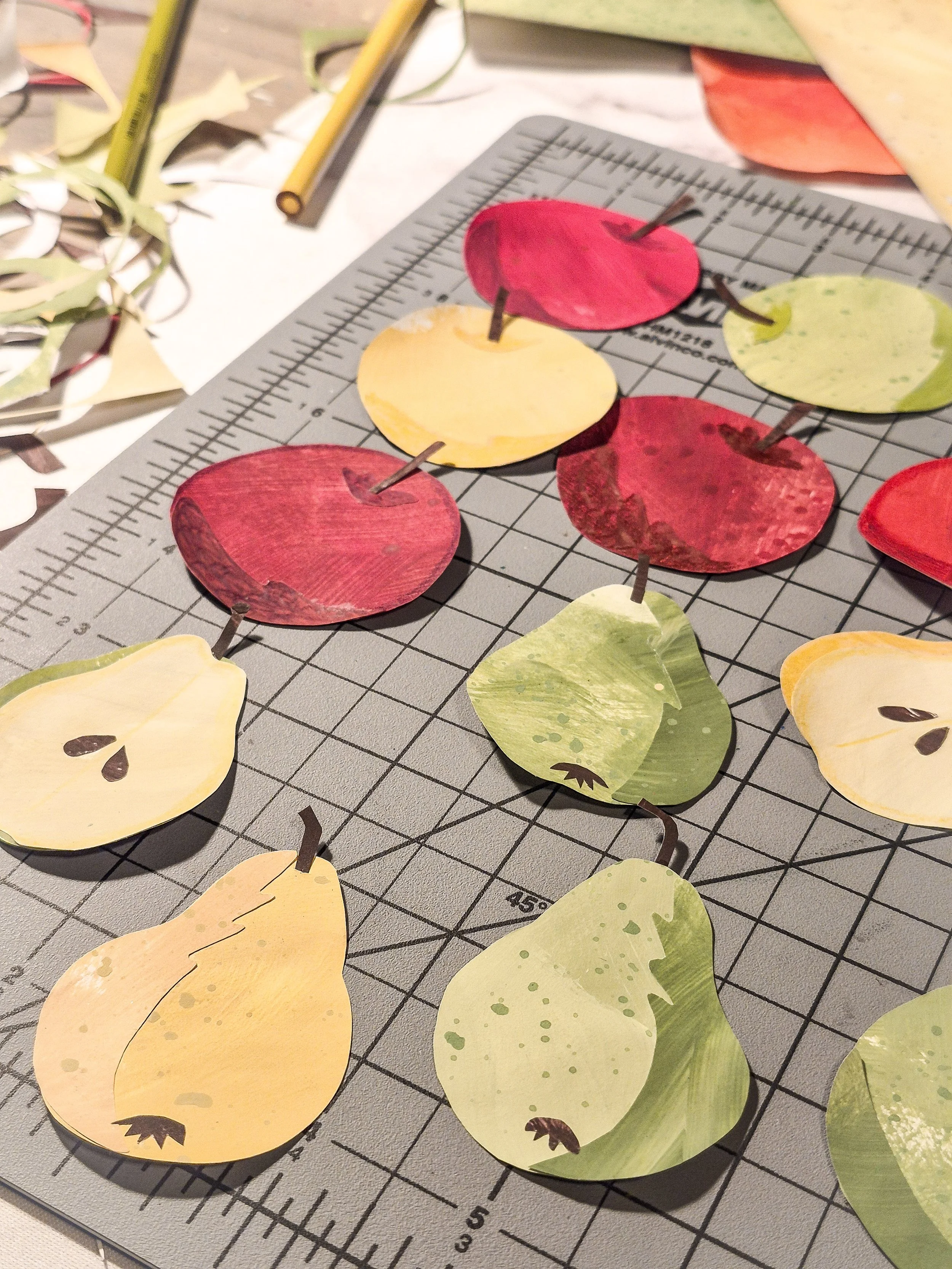 Hand-cut painted paper apple motifs in red, pink, and green