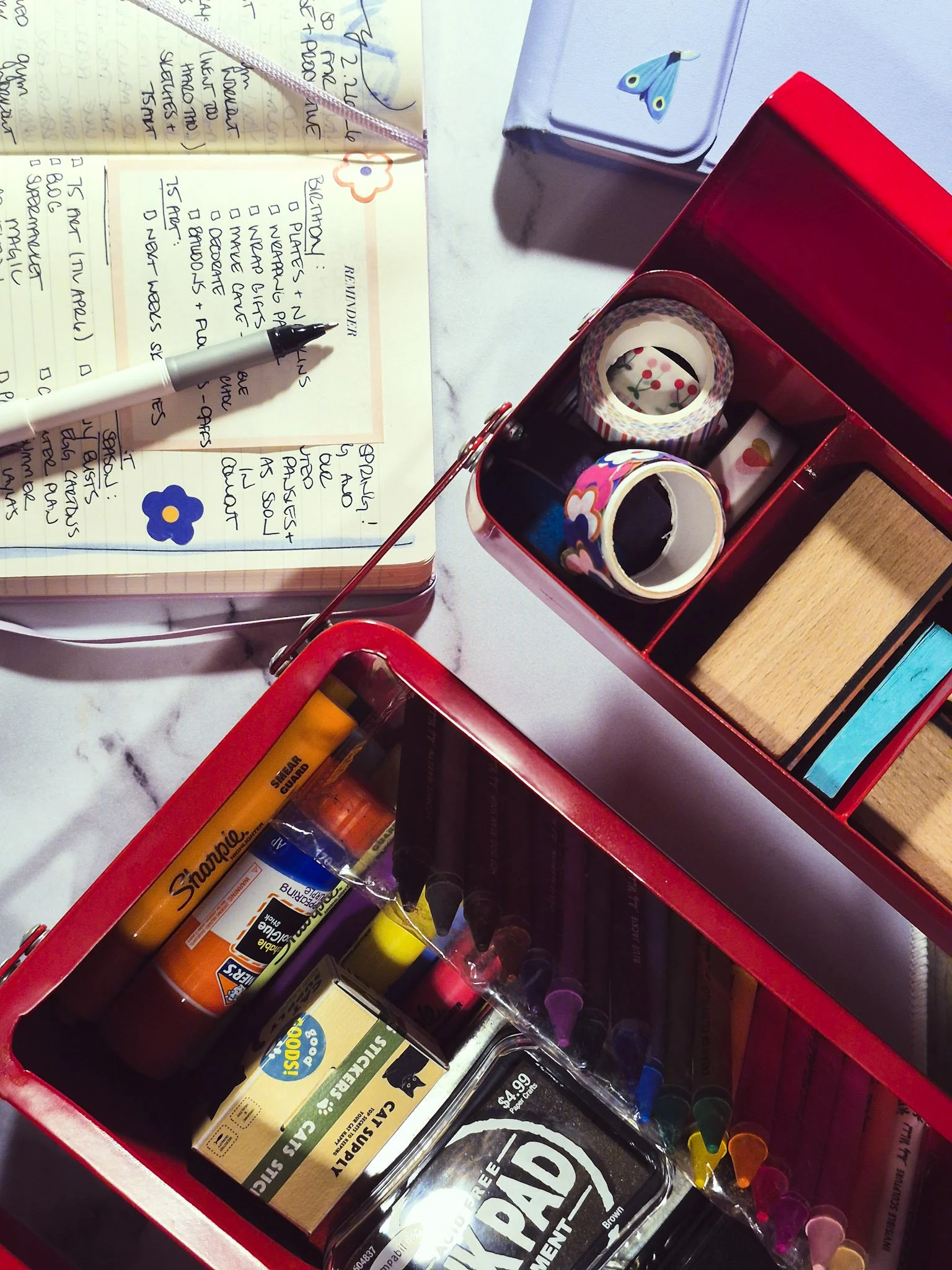 overhead shot of red toolbox full of junk journal supplies. open journal in the back