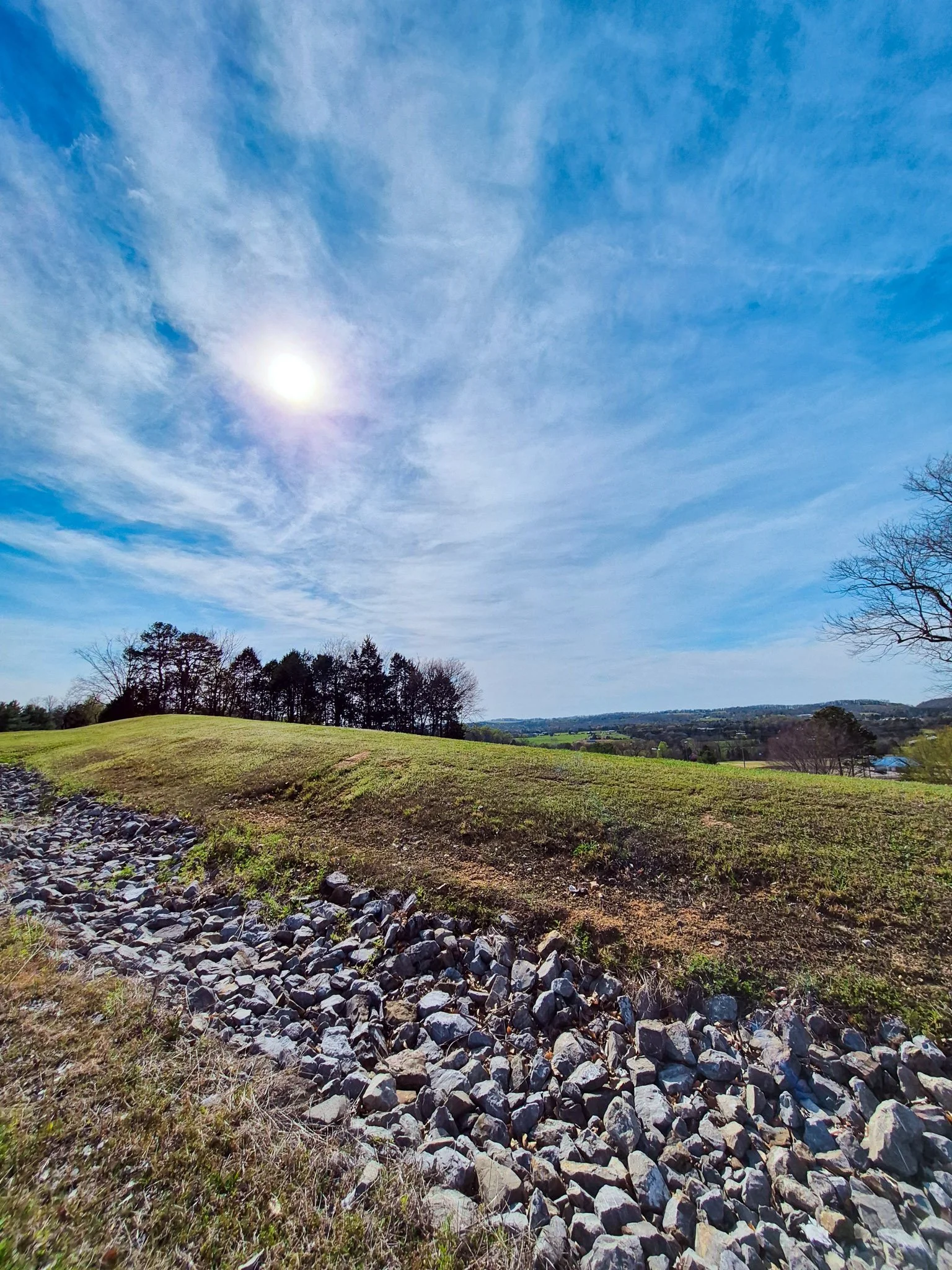 a bright blue sky beaming above an expansive hilly landscape of east tn with spring trees coming into bloom