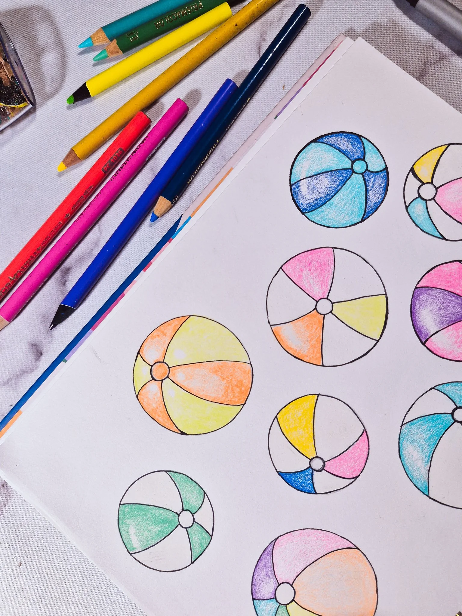 Sketchbook page filled with colored pencil beach ball motif studies for a summer surface pattern collection.