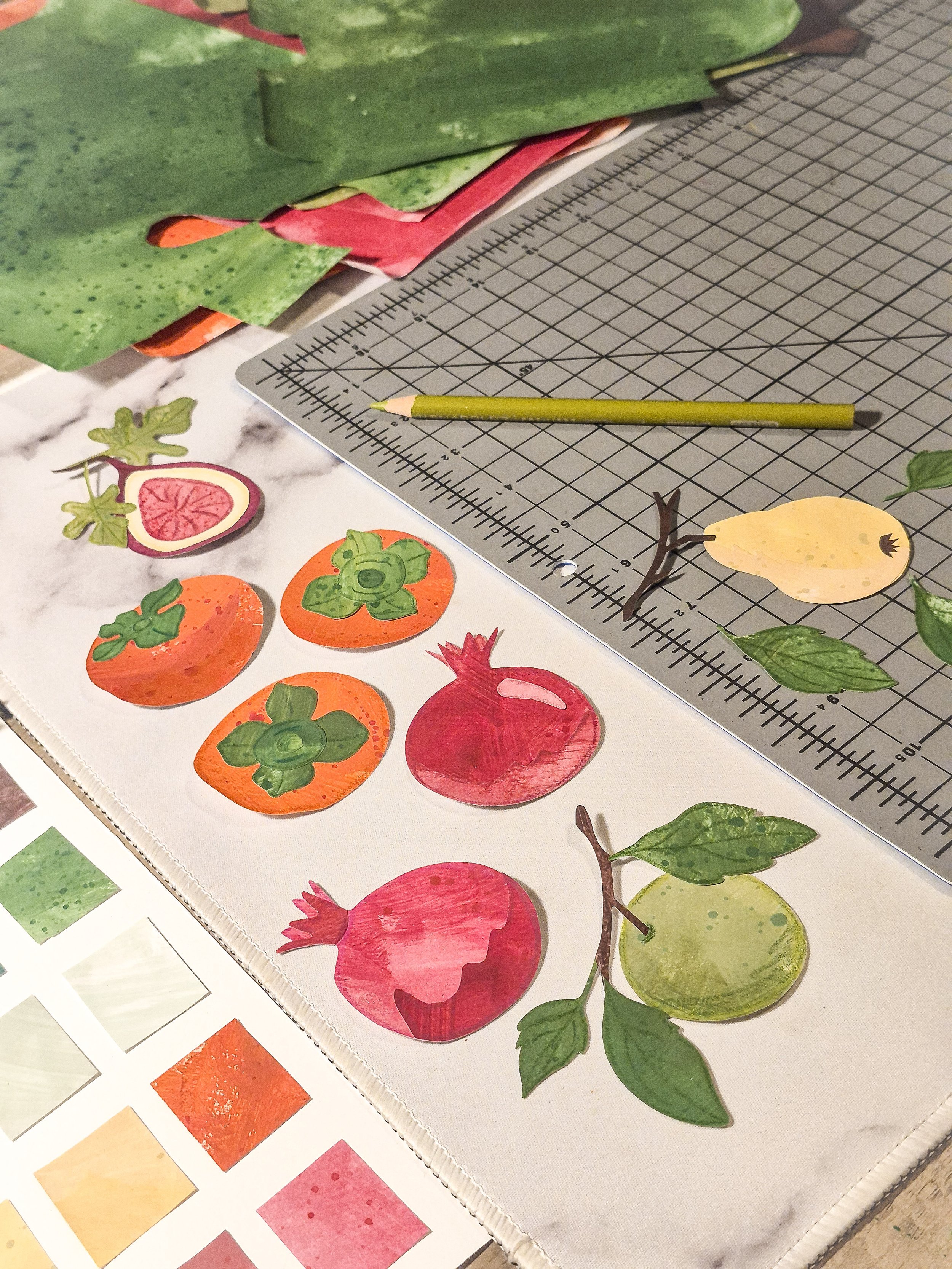 Hand-cut painted paper fruit motifs including pomegranates, persimmons, pears, and leaves