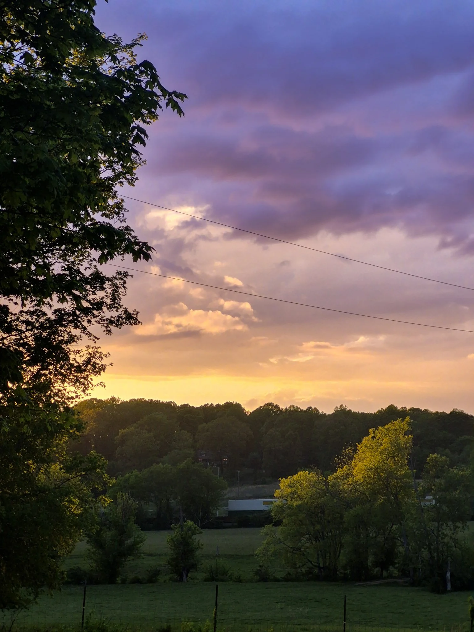 Soft pink, lavender, and glowing orange sunset sky with clouds at the end of a calm spring day