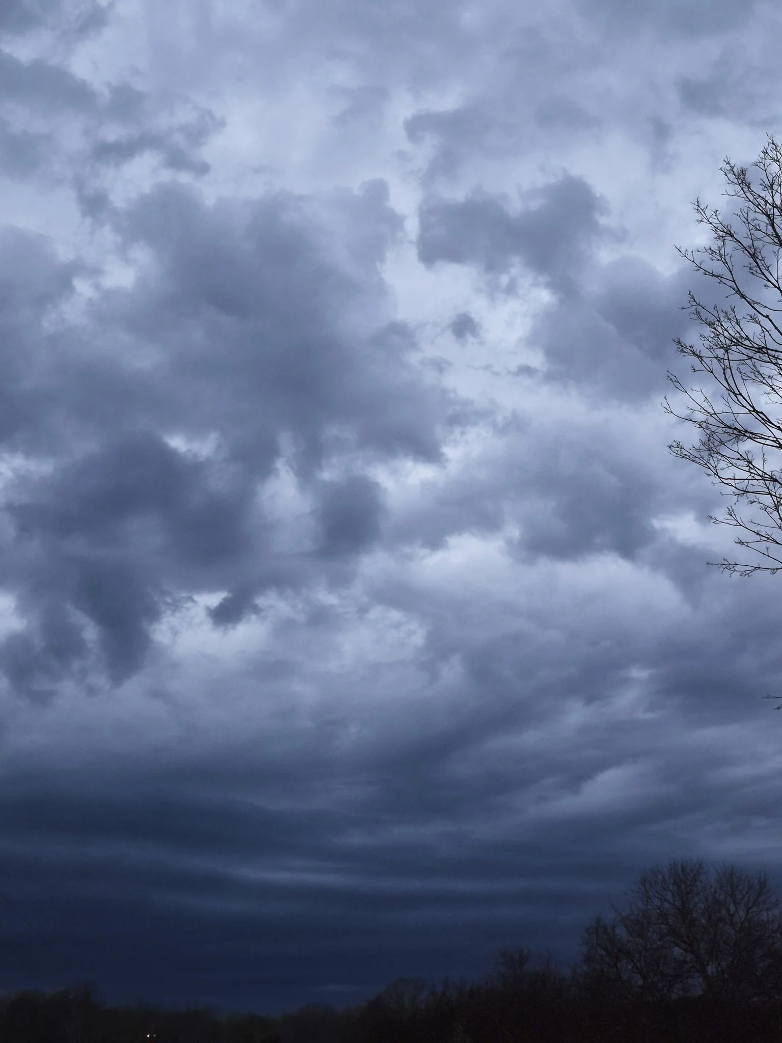 image of a spring thunderstorm rolling in over a ridge covered in white blooming trees