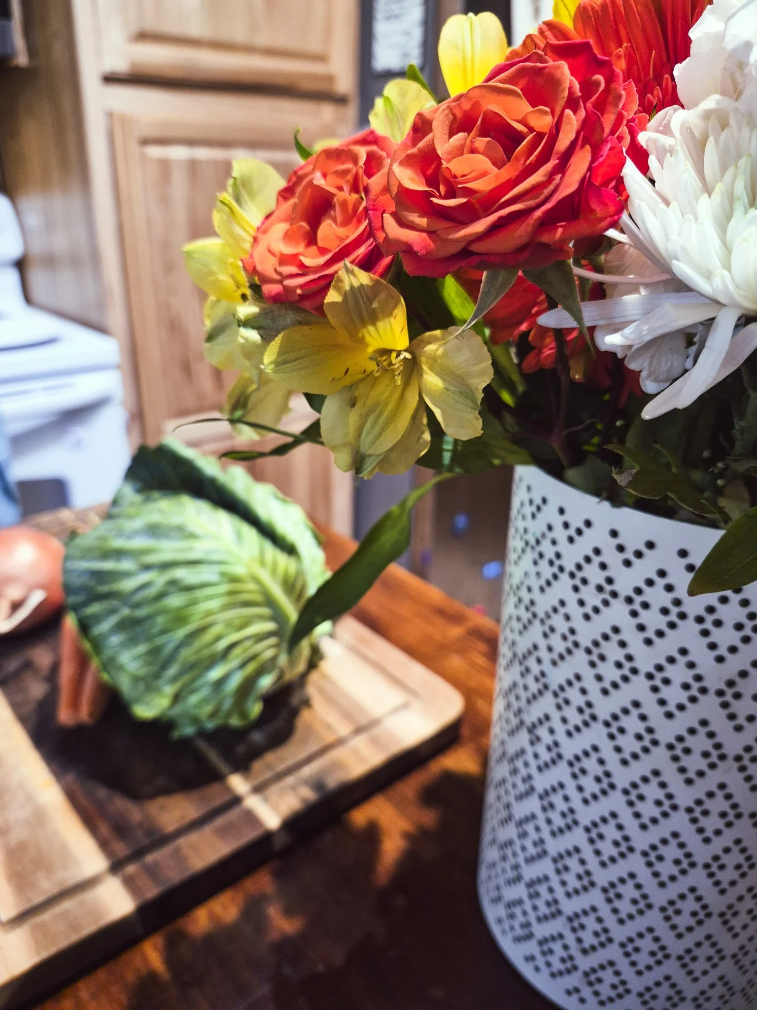 close up image of a bouquet of flowers next to seasonal veg on a cutting board ready for cutting