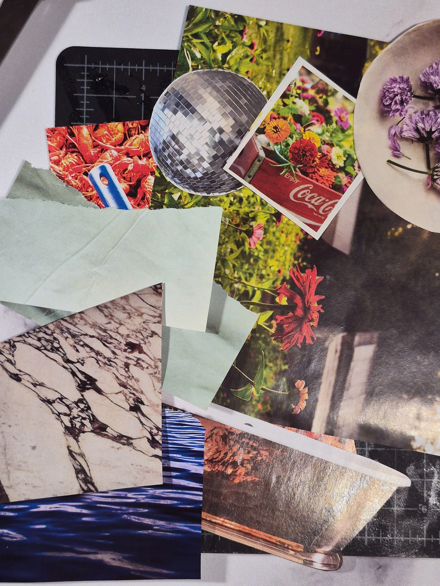 overhead desk shot of magazine collage cutouts on a black cutting mat