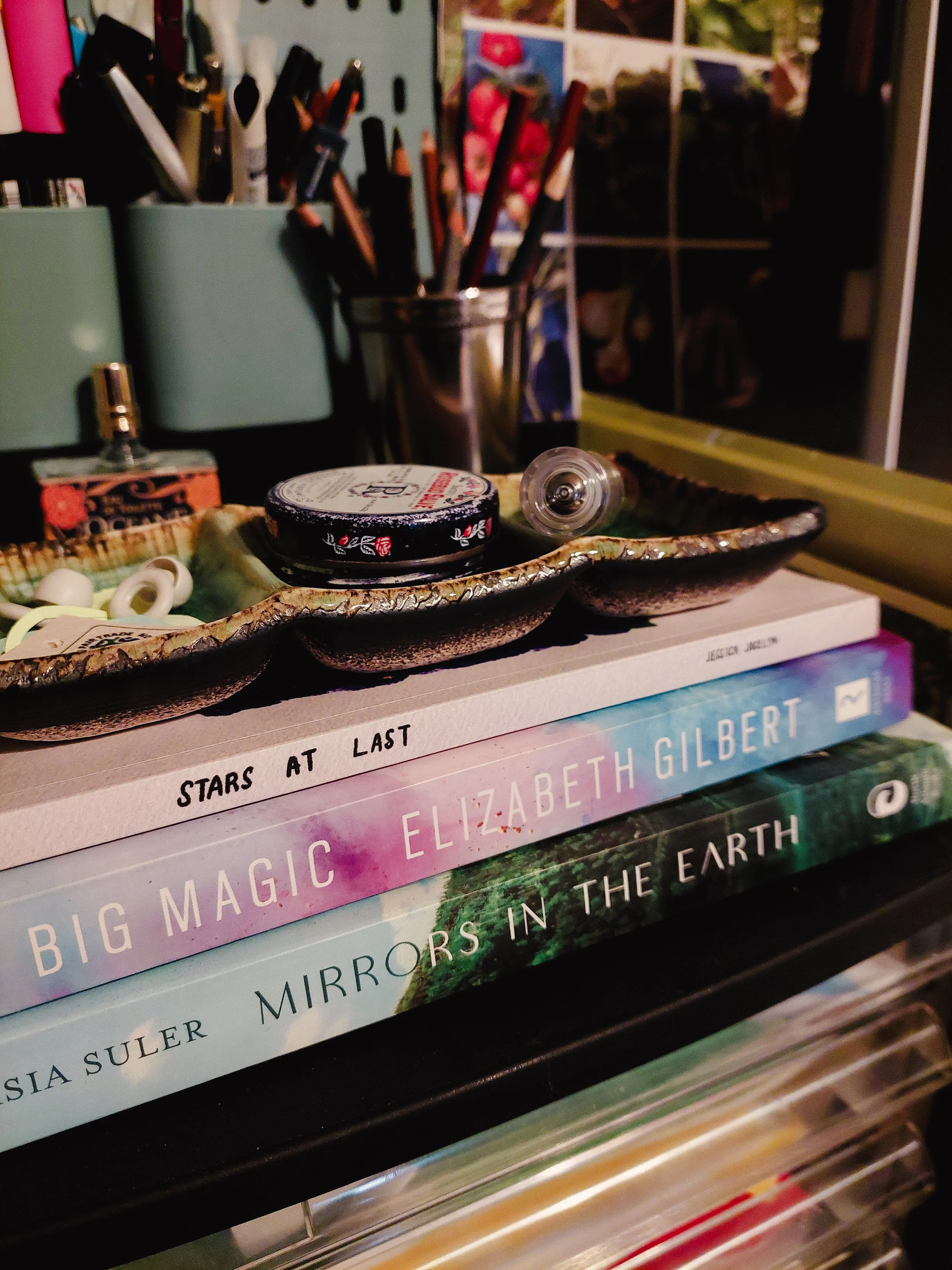 cozy desk shot with a book stack and art supplies