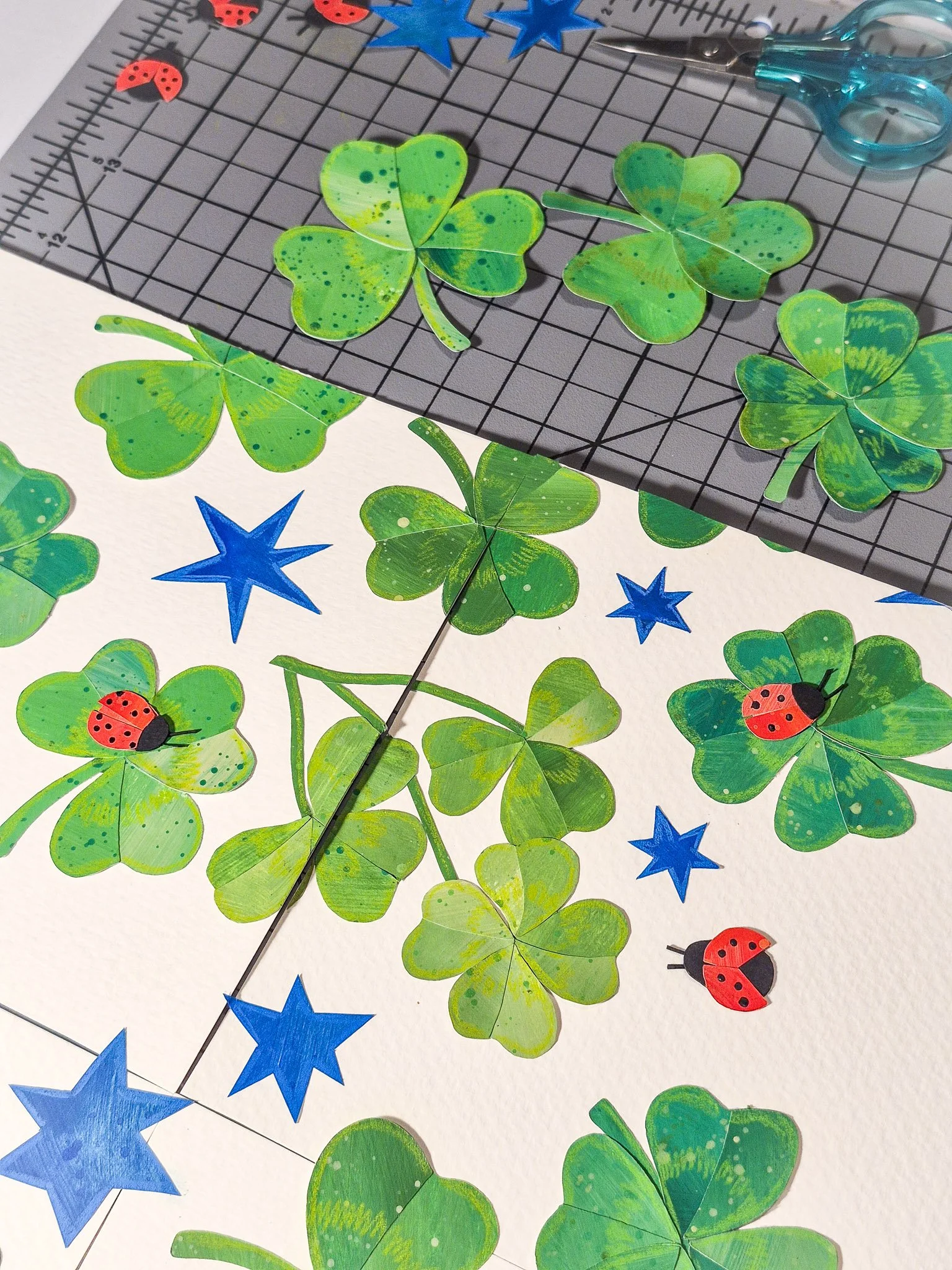 Handmade paper collage featuring clovers, stars, and ladybugs arranged into a repeating pattern design