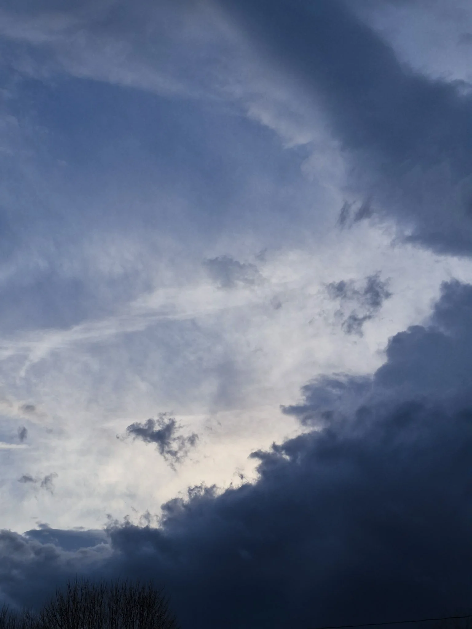 image of an ominous sunset hidden behind thick navy clouds rolling in with the spring thrunderstorms