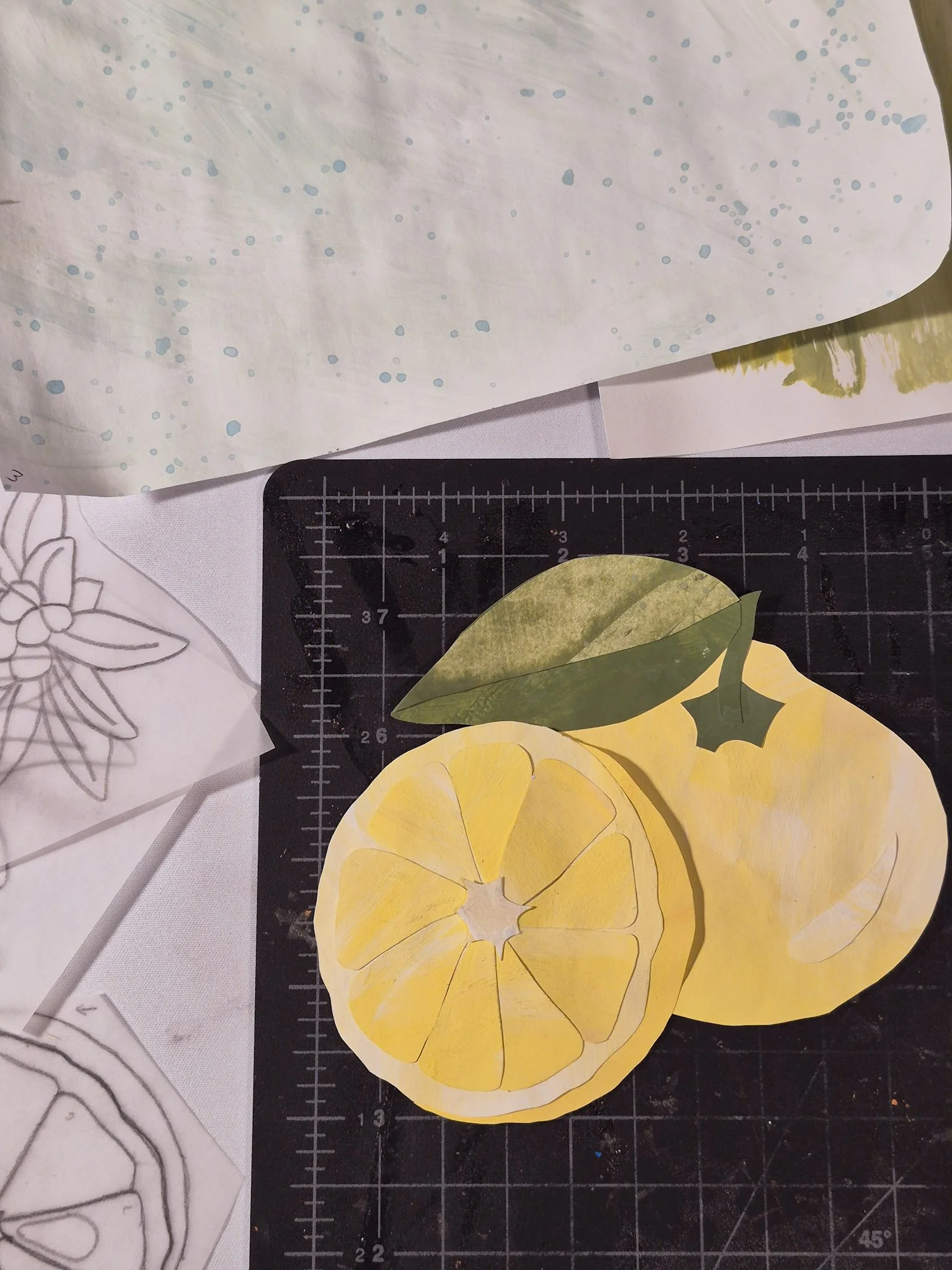 yuzu fruit painted paper collage on a black cutting mat with painted papers and templates around on the desk