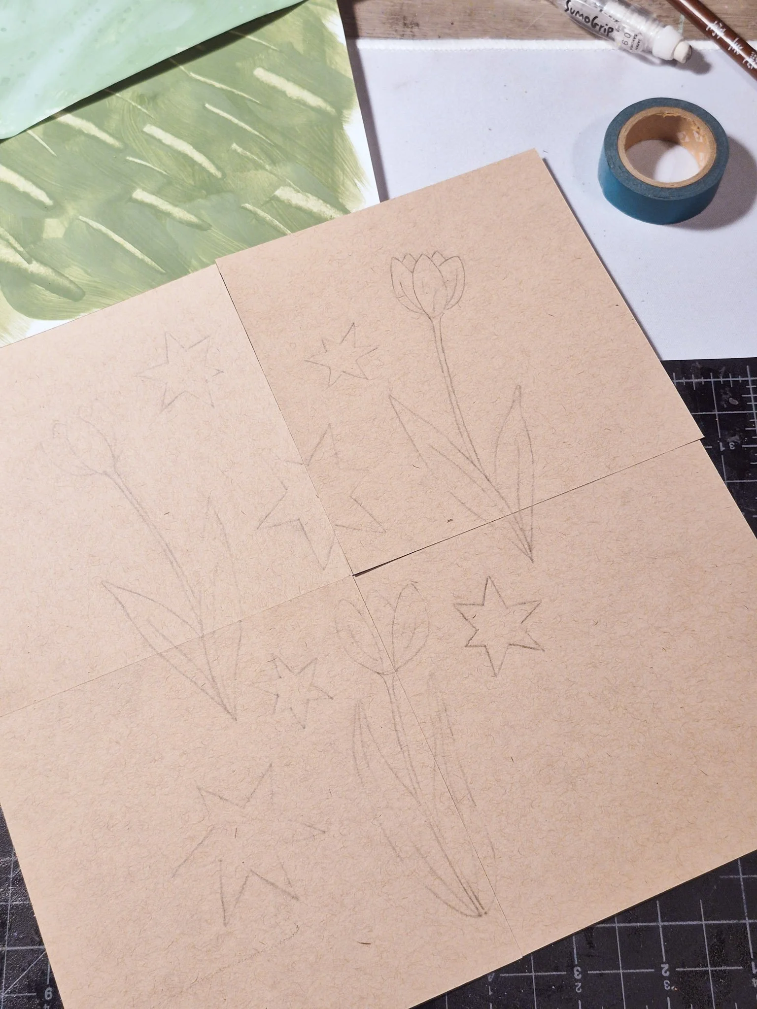 A simple design of tulips and retro starbursts drawn across four connected paper squares, with elements crossing the seams.