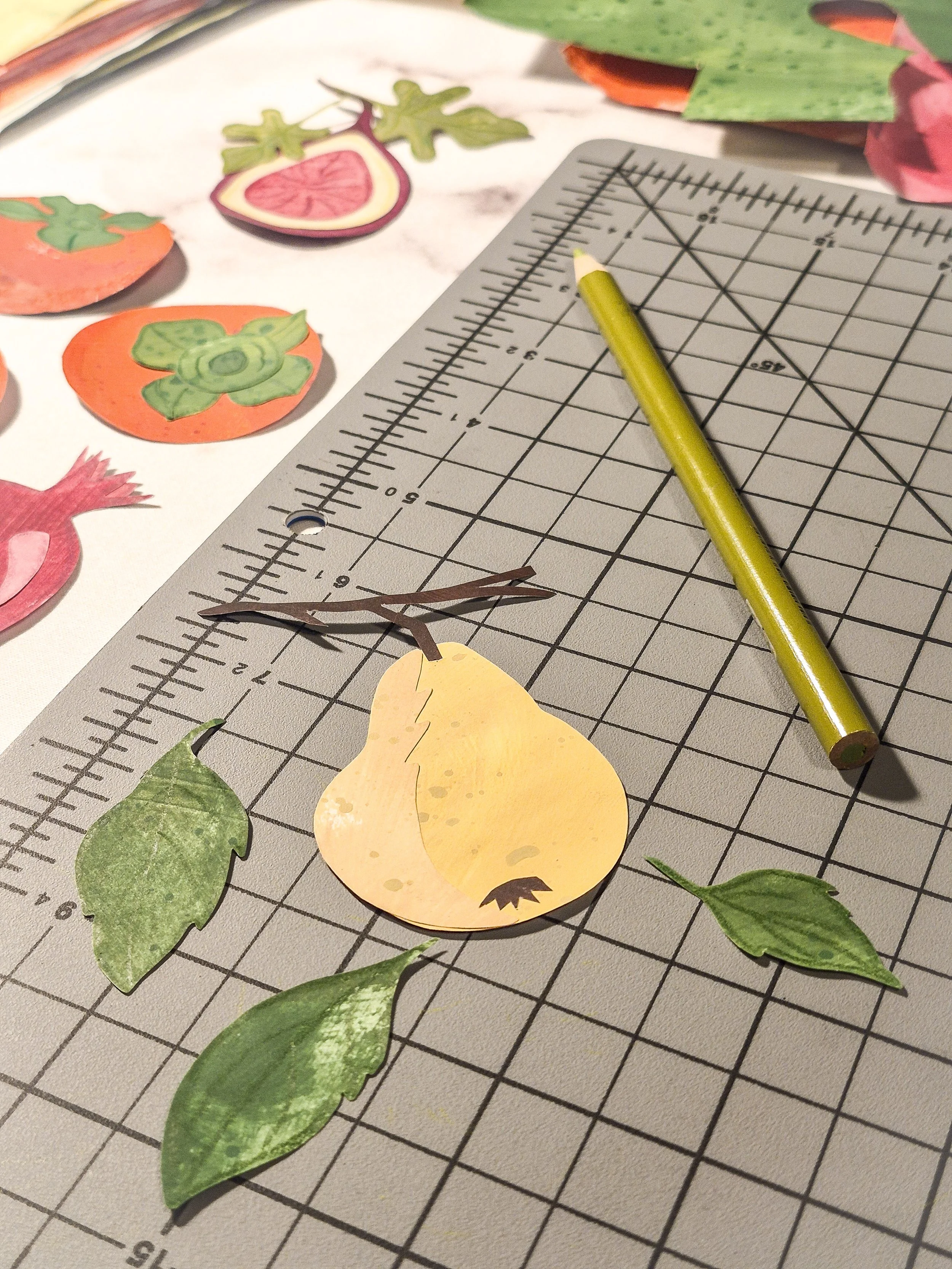 A hand-cut painted paper pear motif with leaves and a brown paper stem