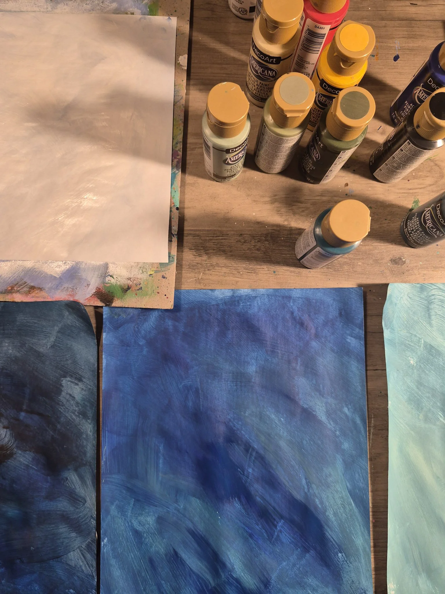 Overhead desk shot with painted papers and small bottles of paint