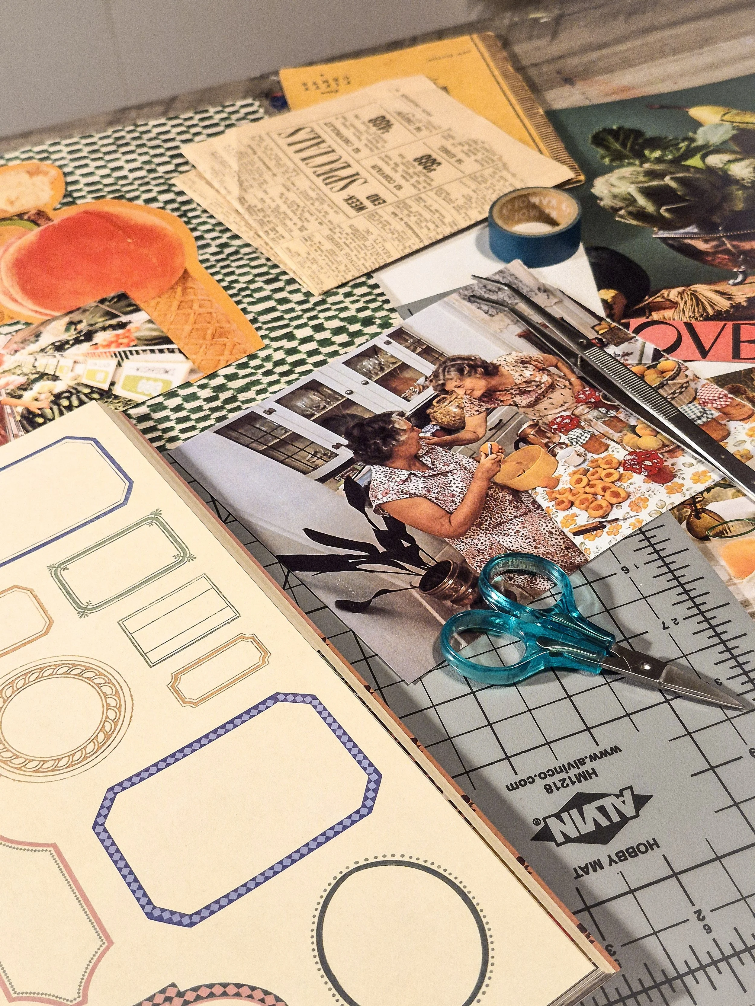 Vintage magazine pages featuring food, kitchen scenes, and domestic imagery arranged among colorful collage papers and scissors on a worktable.