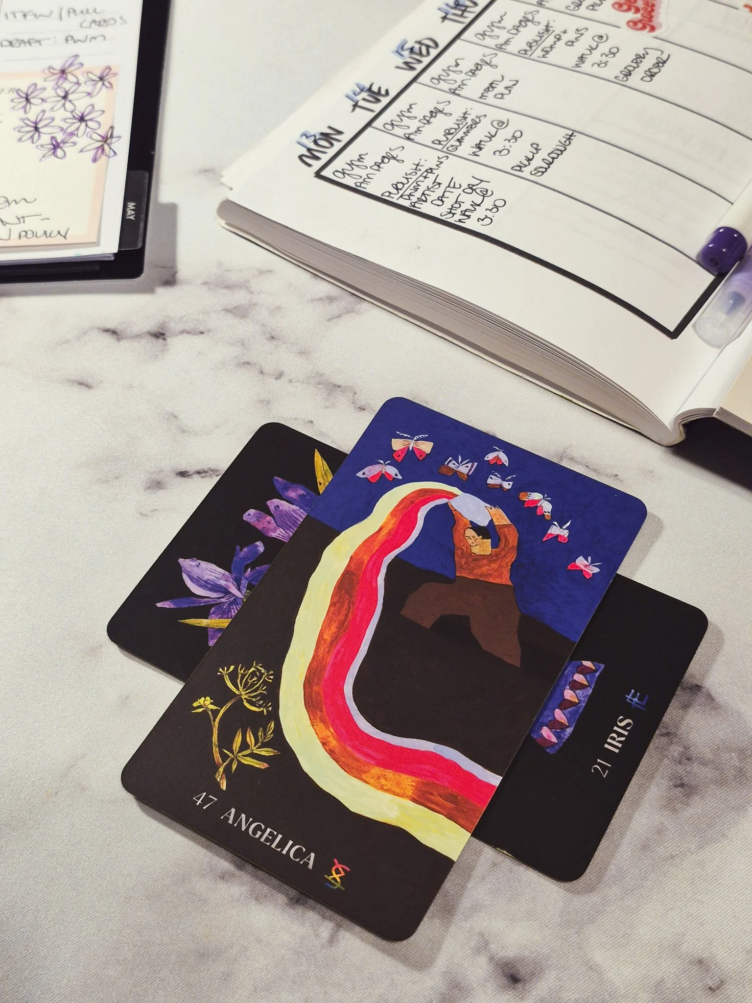 Creative weekly planning spread with handwritten goals, intentions tracker, sticky note to-do list, colorful pen doodles, botanical oracle cards, and cozy stationery setup.