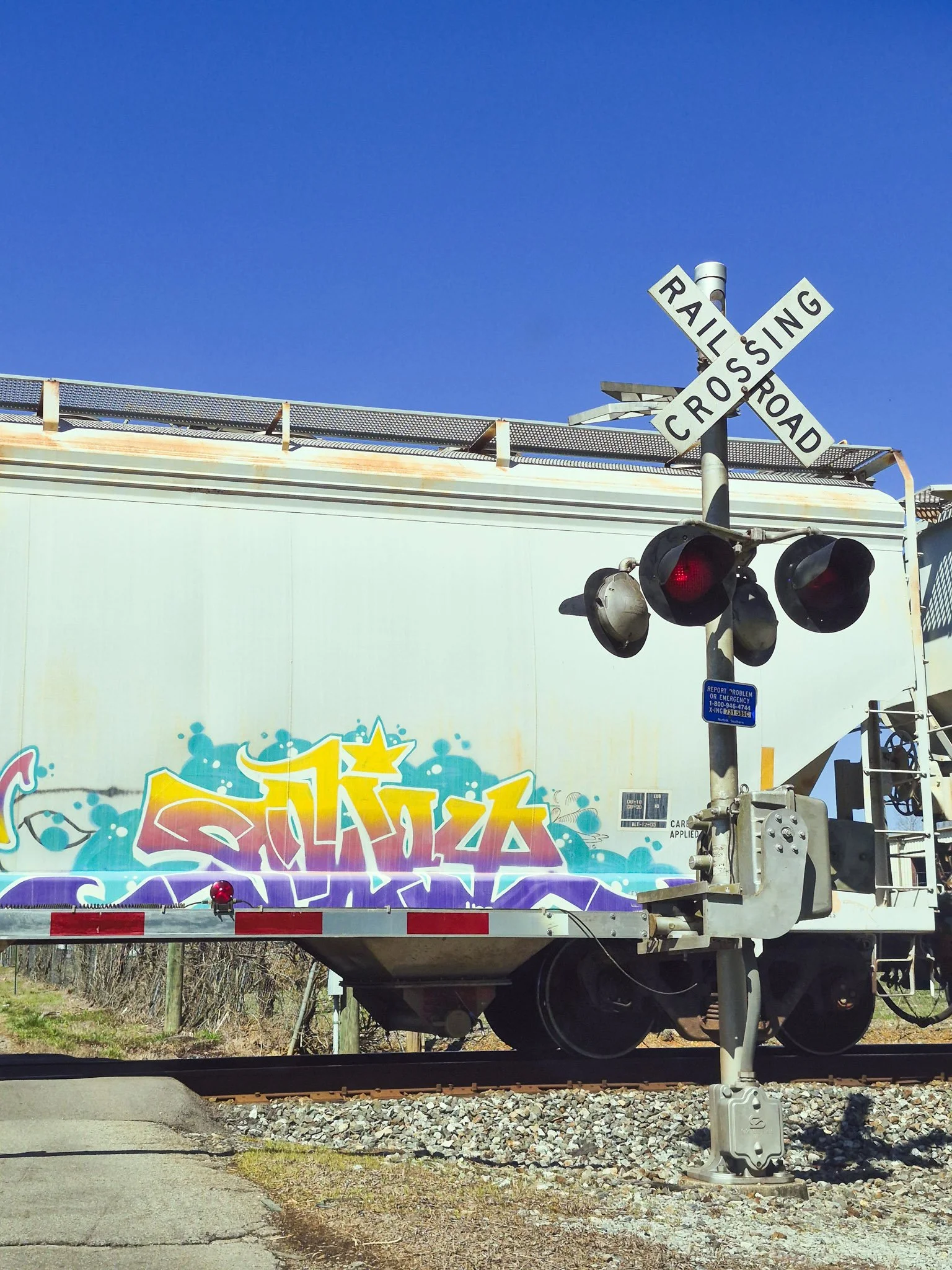 image of a graffiti tag on a moving train taken while stopped at the crossing