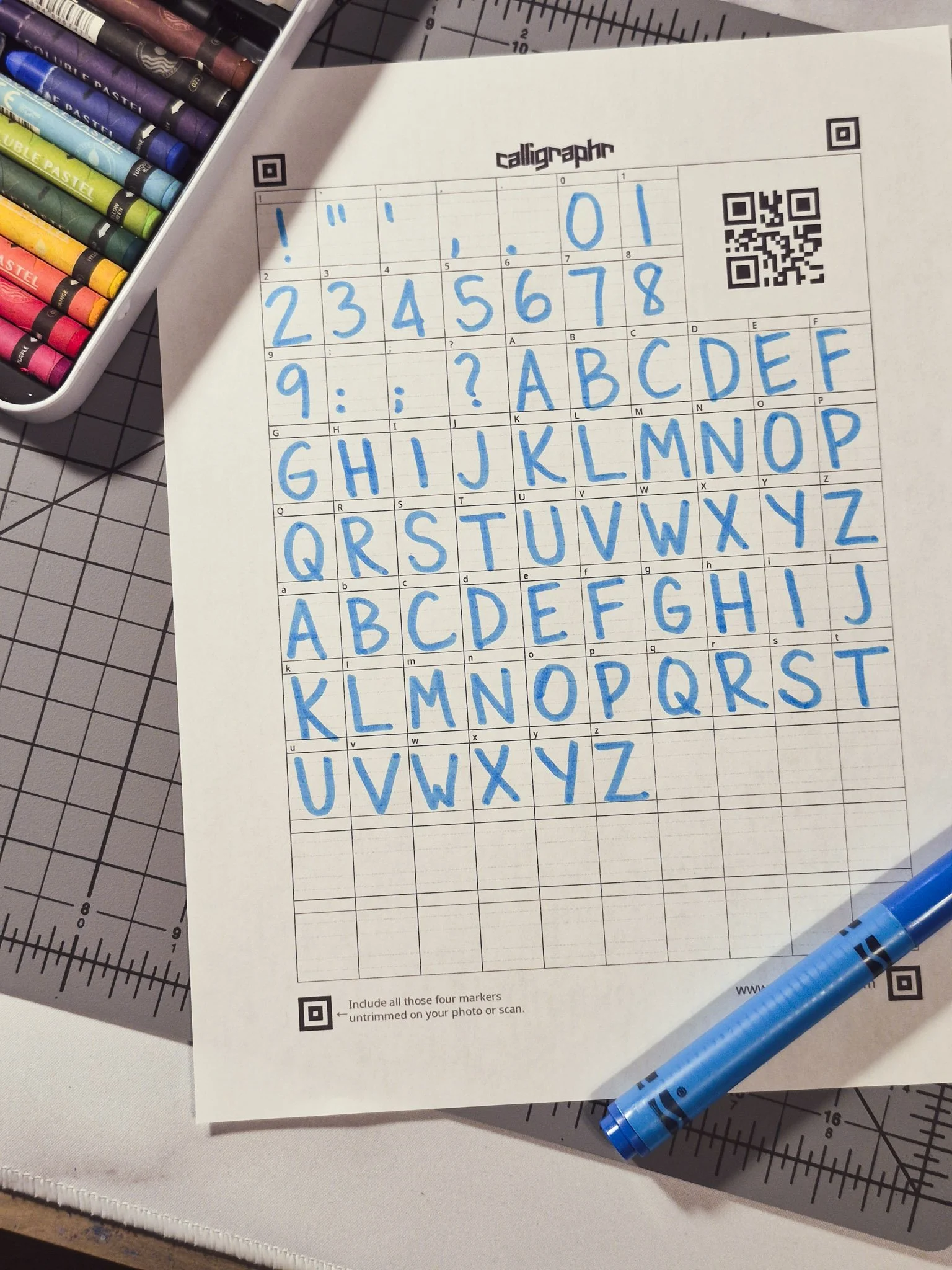 cozy workspace with art supplies and a font template from calligraphr filled in with a crayola marker