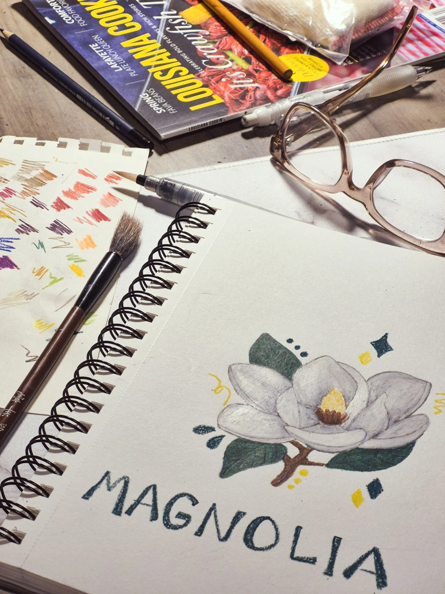 desk shot of a WIP sketch of a magnolia with water pastels