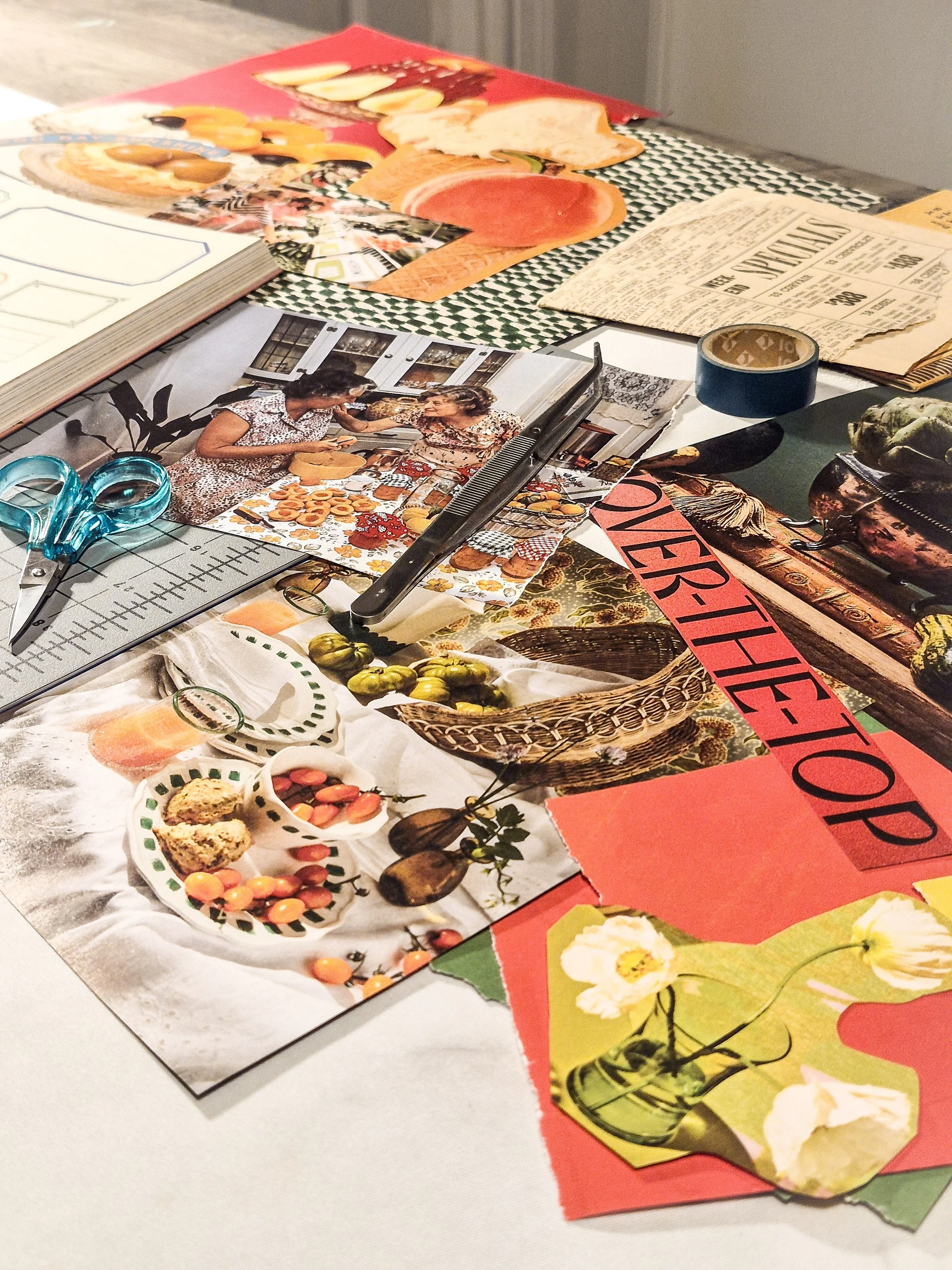 A collage workspace covered with vintage magazine food imagery, painted papers, scissors, tape, and a cutting mat.