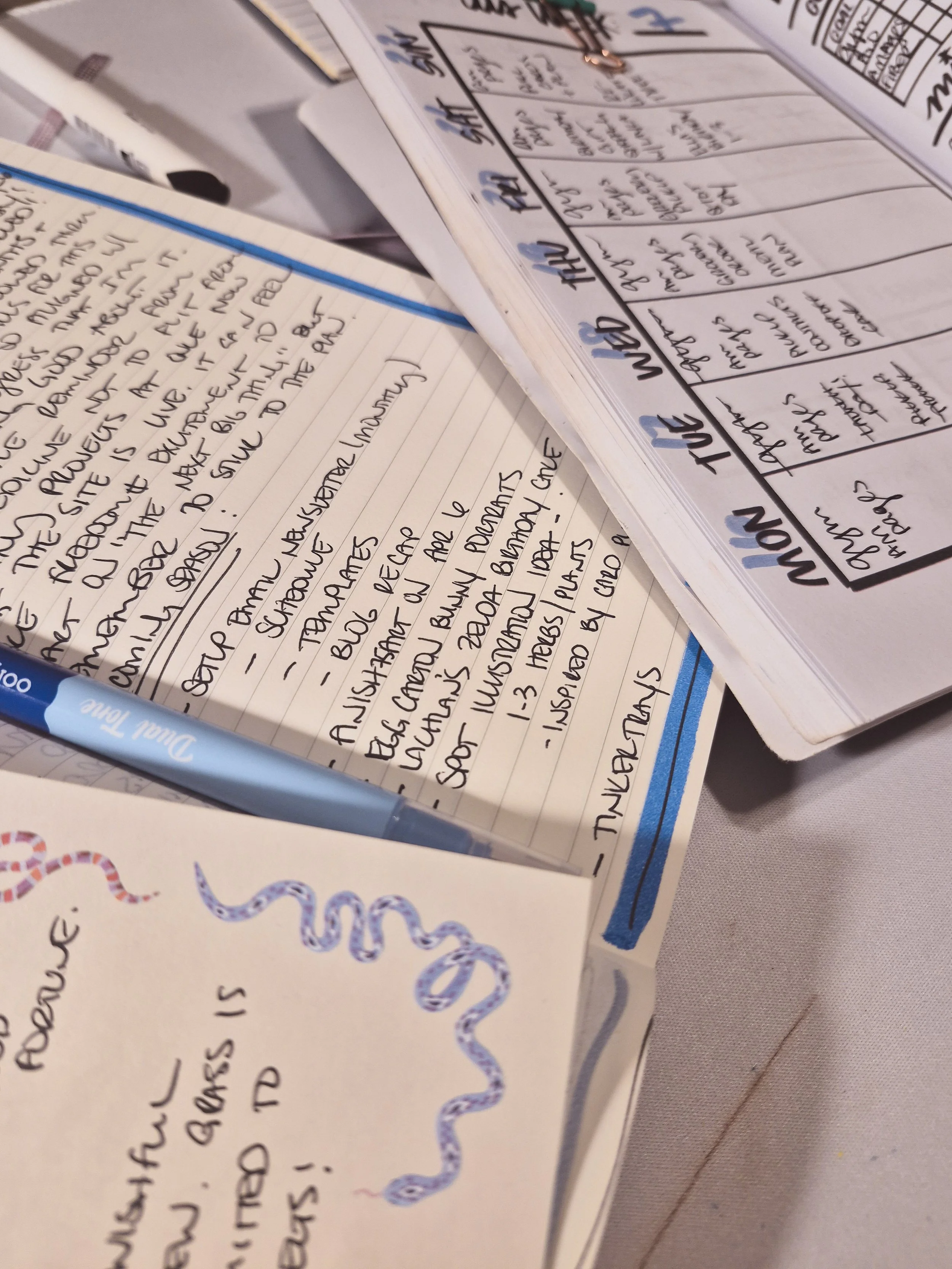 close up desk shot with several notepads and planners strewn about with white marble background