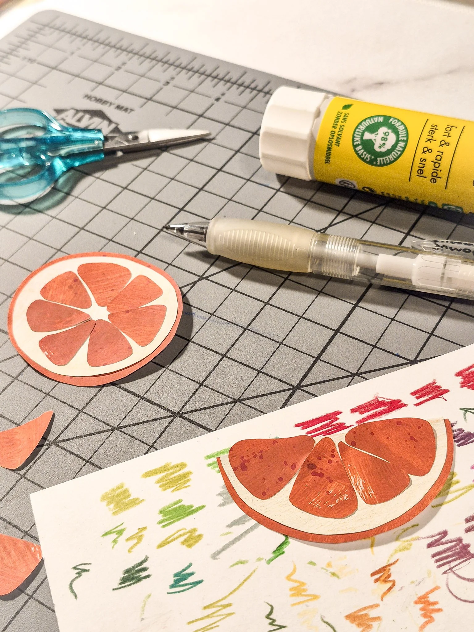 Painted paper collage pieces on a cutting mat.
