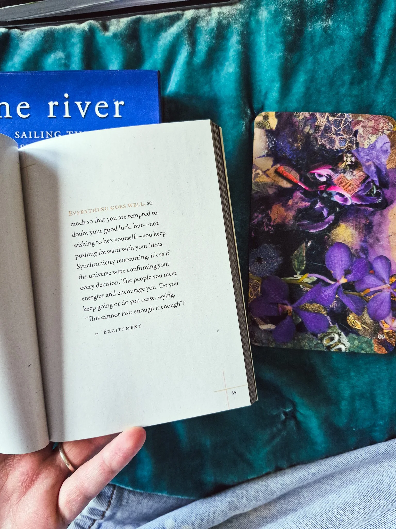flat lay image of a tarot card from The River deck and open guidebook next to it