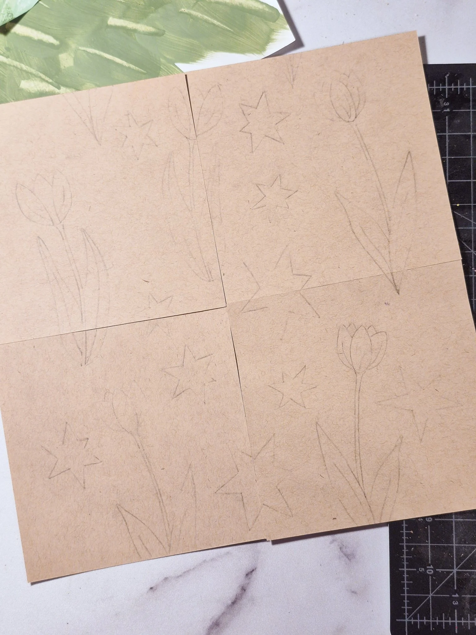 A simple tulip and retro starburst design drawn across four connected paper squares, with elements crossing the seams, avoiding the edges.