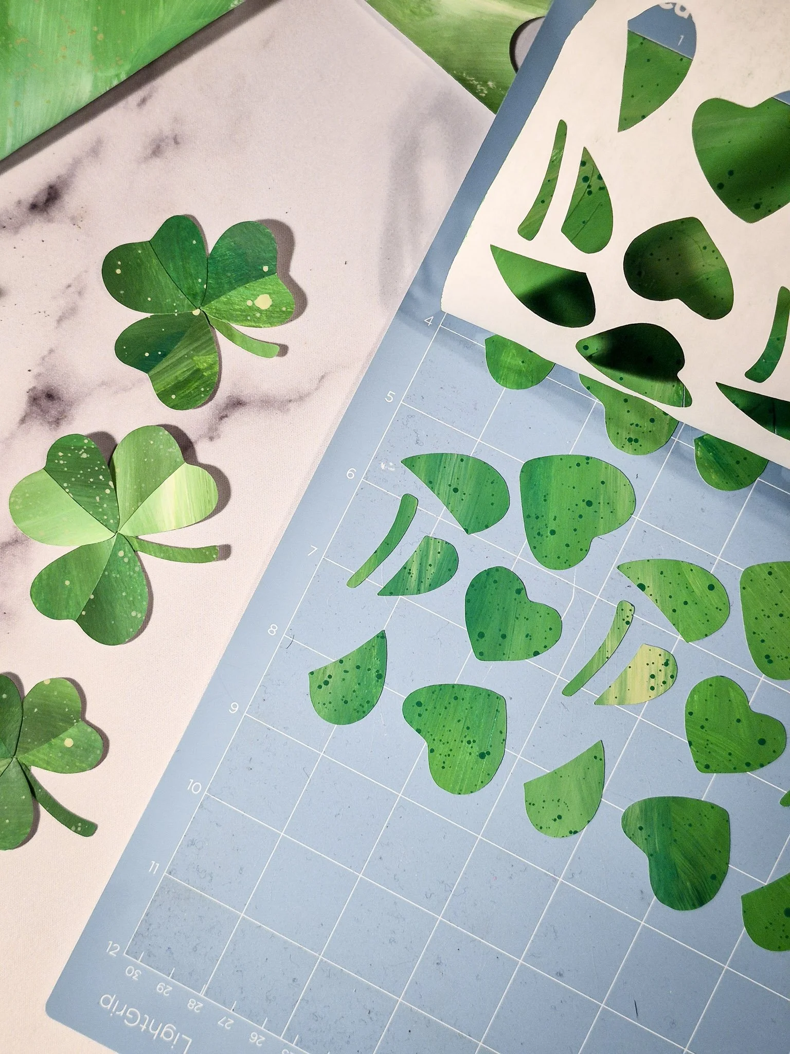 Hand-painted green paper cut into clover shapes using a Cricut machine for an analog collage repeat pattern