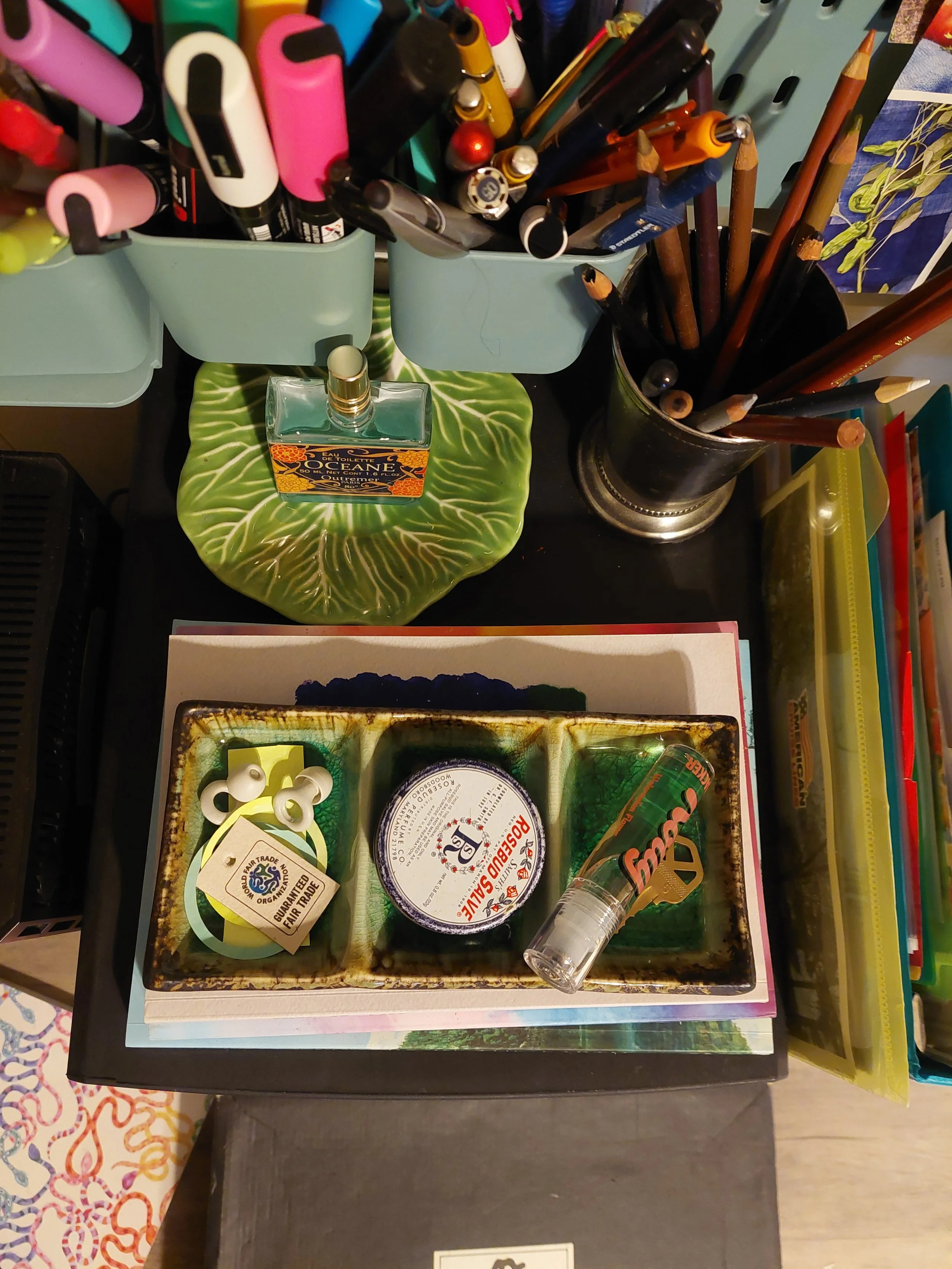 overhead shot of cozy desk setup with art supplies and perfume bottles and notebooks